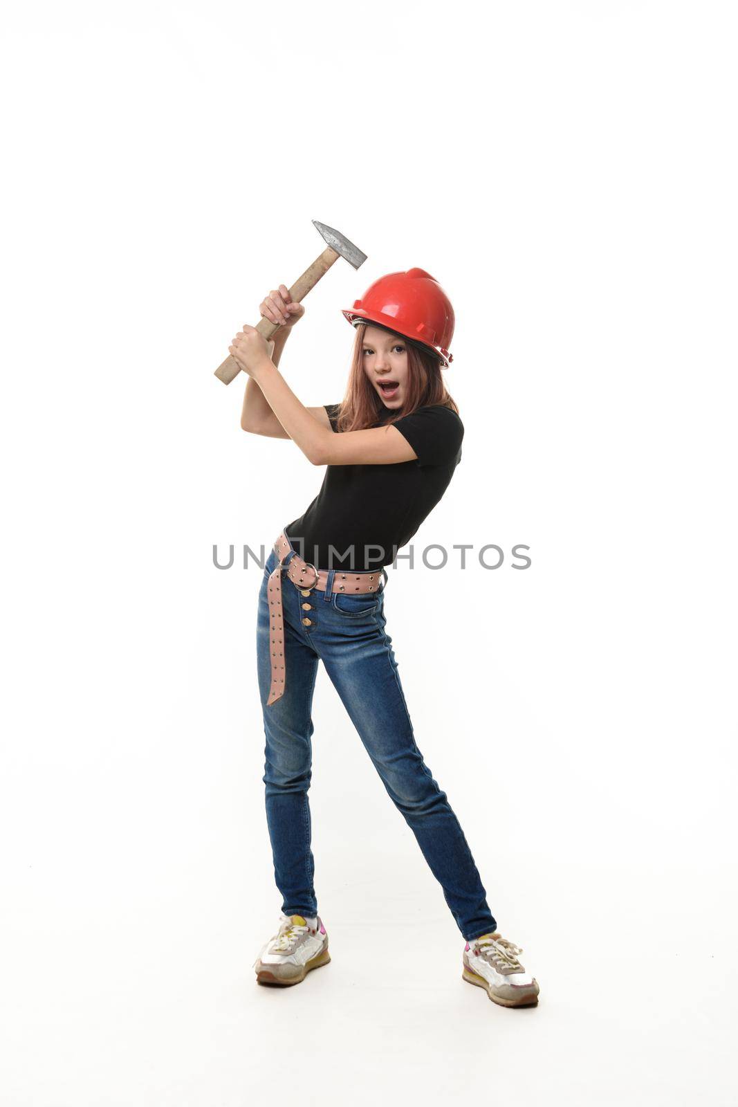 A girl in a helmet hits herself on the head with a hammer