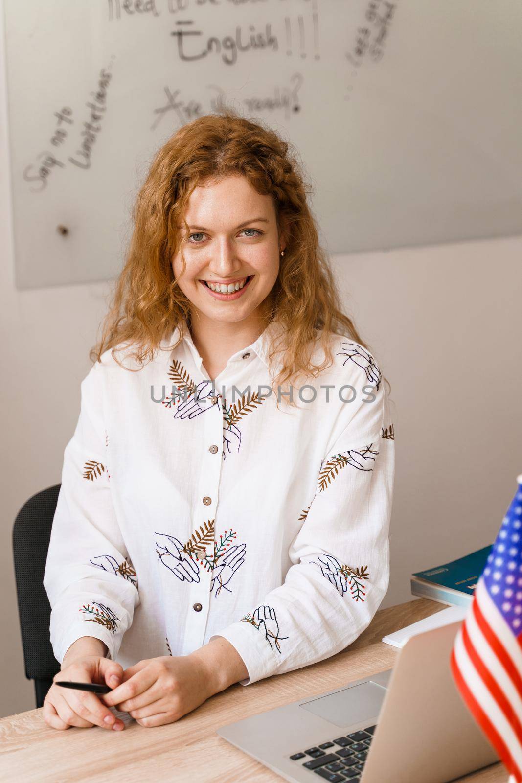 Close-up portrait of a beautiful smiling student on bright background. Happy ginger female teacher smiling to her colleagues. by Rabizo