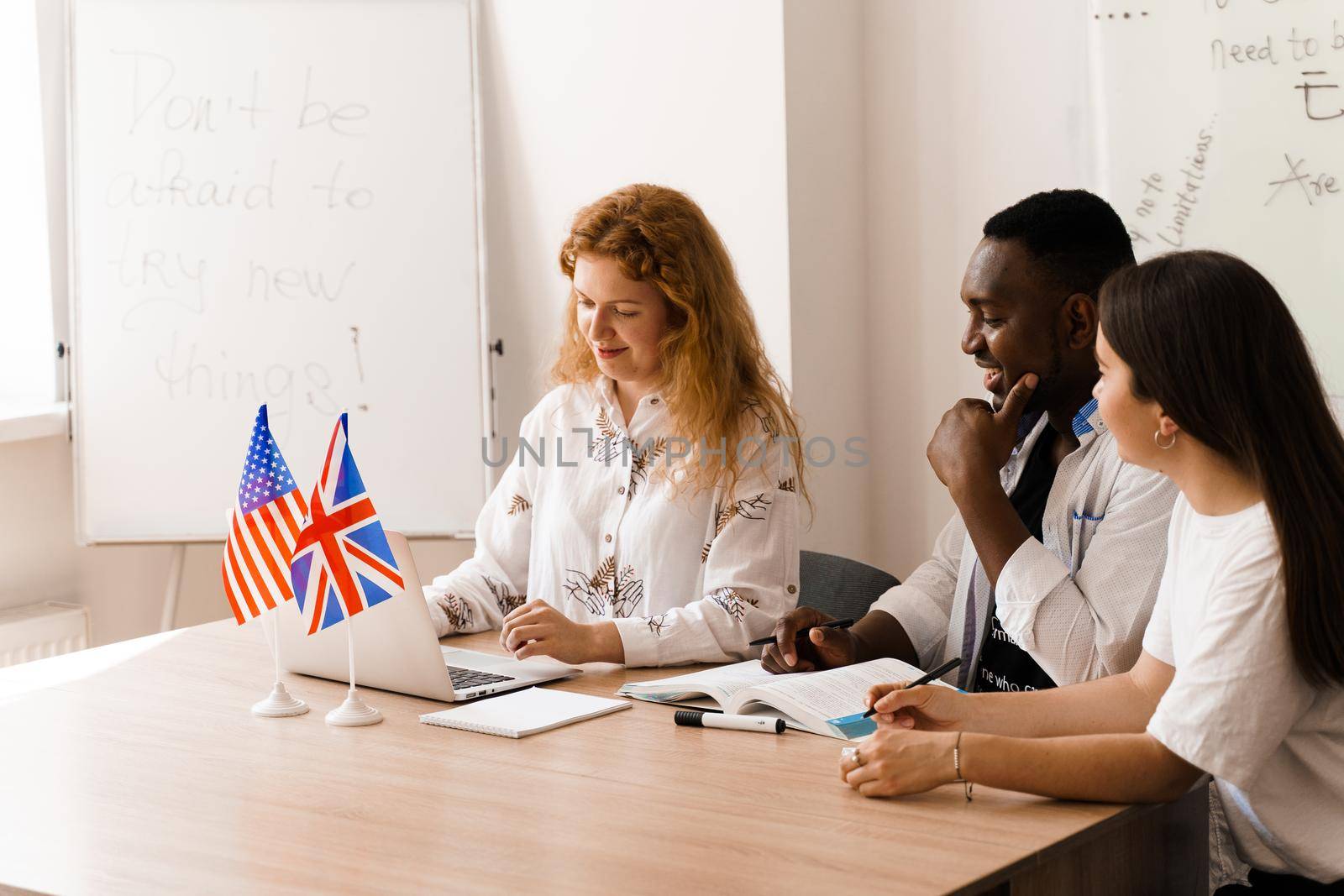 Online multiethnic attractive group of teachers study and laught, discuss something. Remote work in multinational group with laptop.