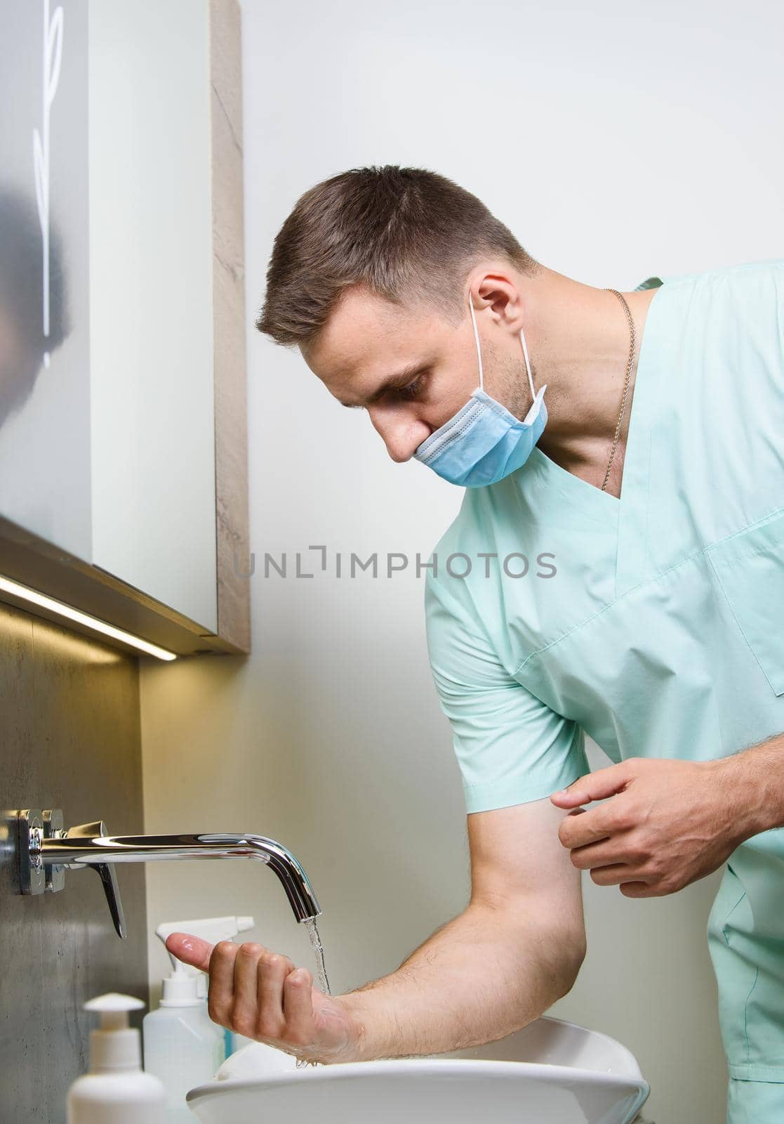 Professional surgeon washes his hands in clinic before surgery operation. Procedure to stop coronavirus