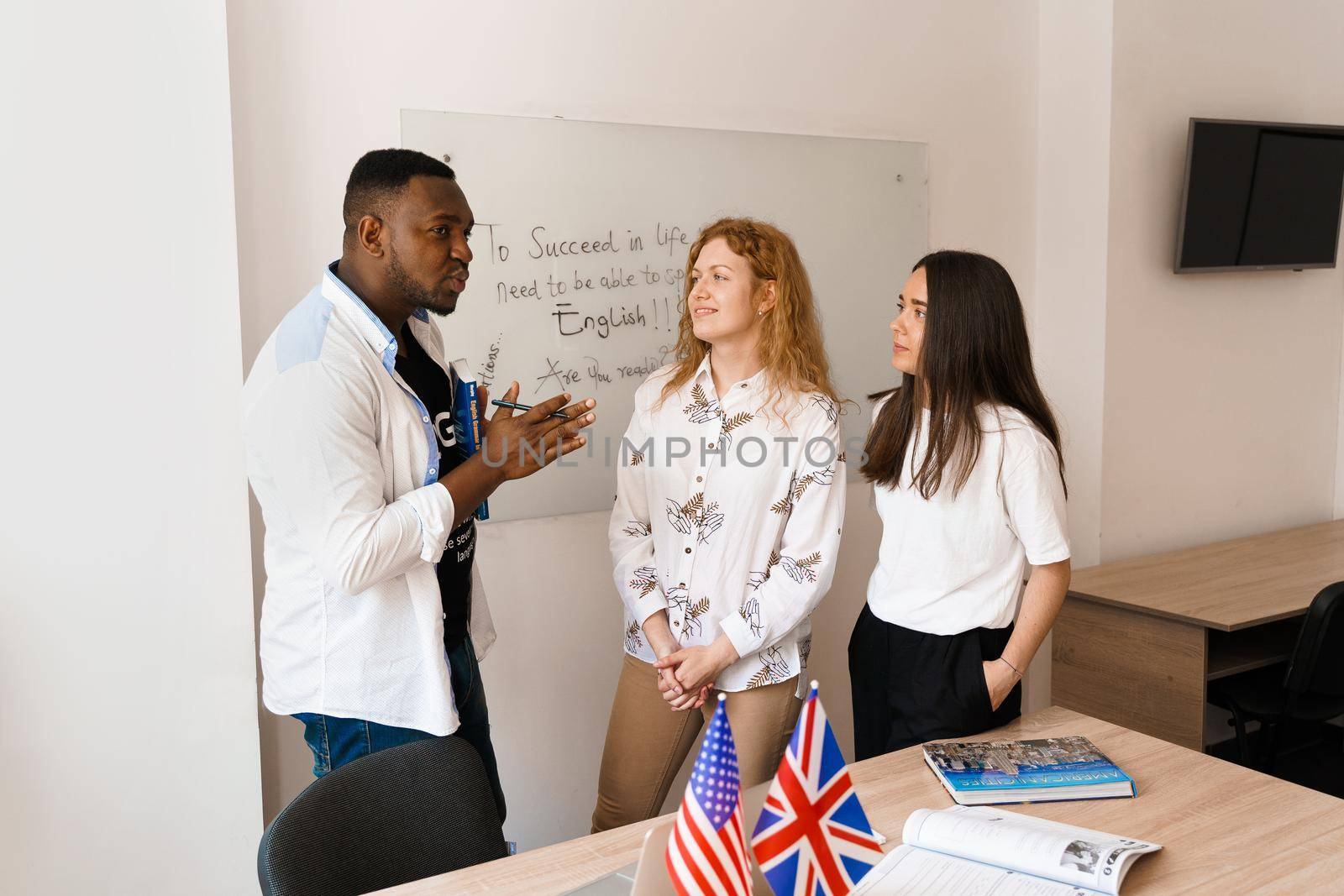 Multiethnic happy students and black teacher study foreign languages and smile and laught together in class. Studing with laptop.