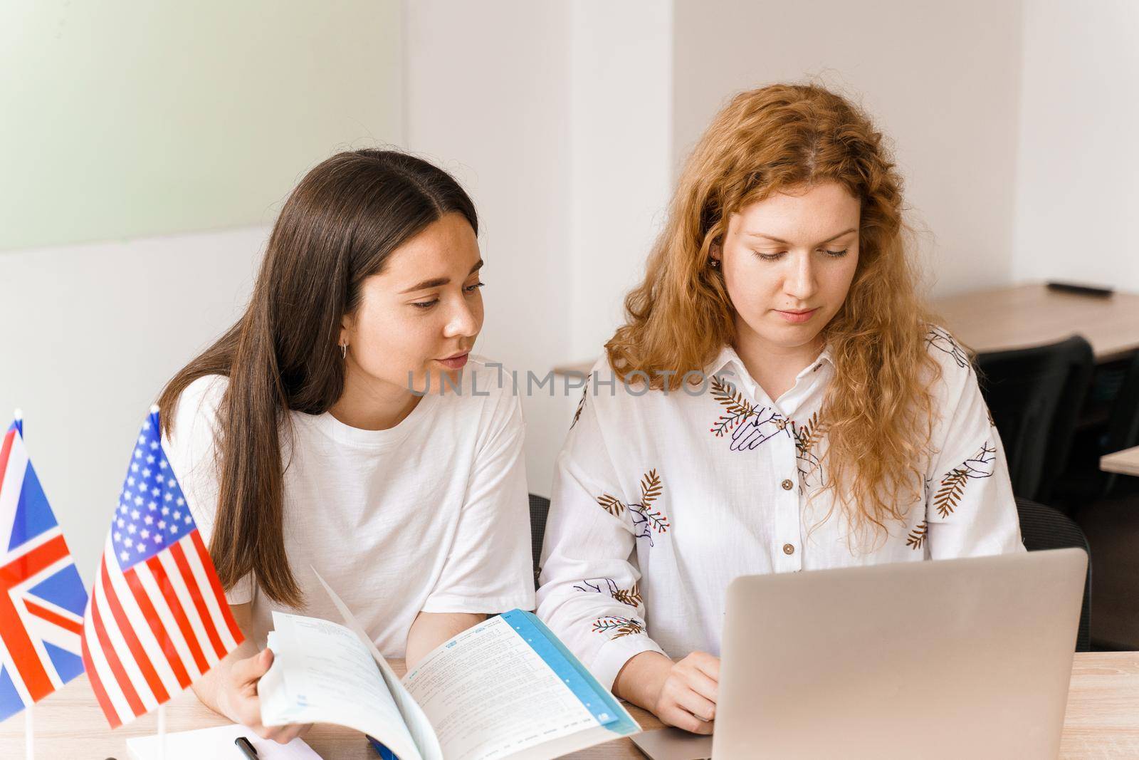 Teacher of english asks student in white class using laptop. 2 girls student answers to teacher. Working in group. Study english and british language.