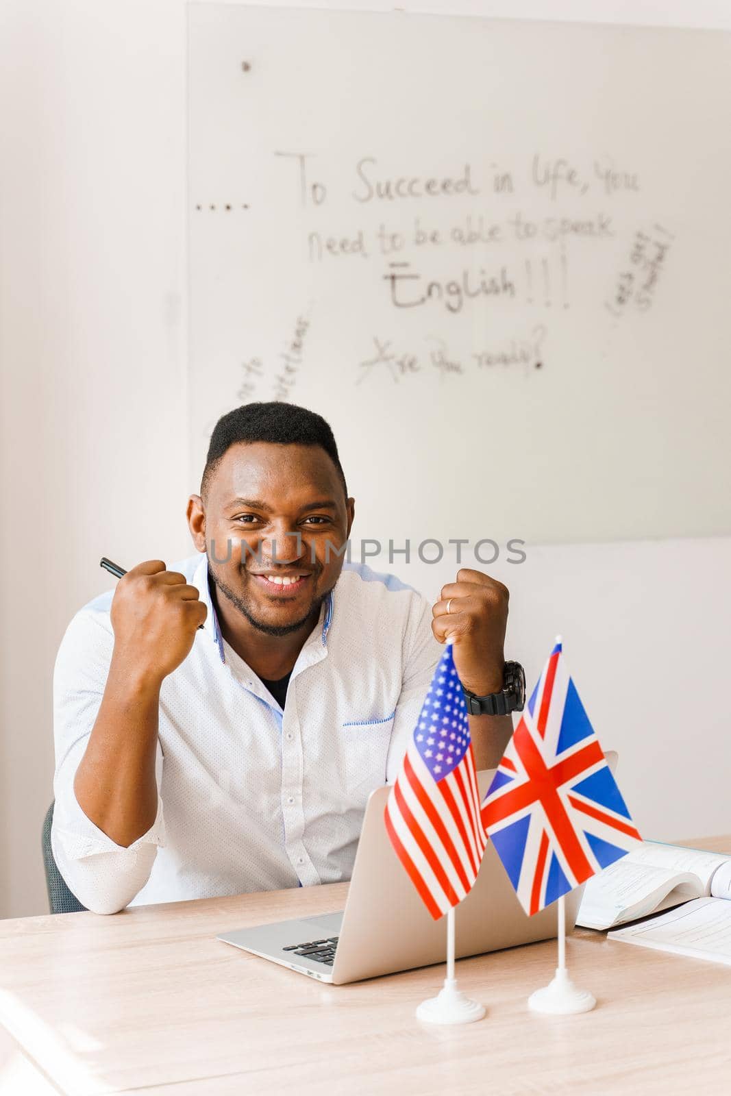 Black handsome man smiles, grimacing and uses his laptop for online work according social distancing. Speaking by web camera with colleagues.