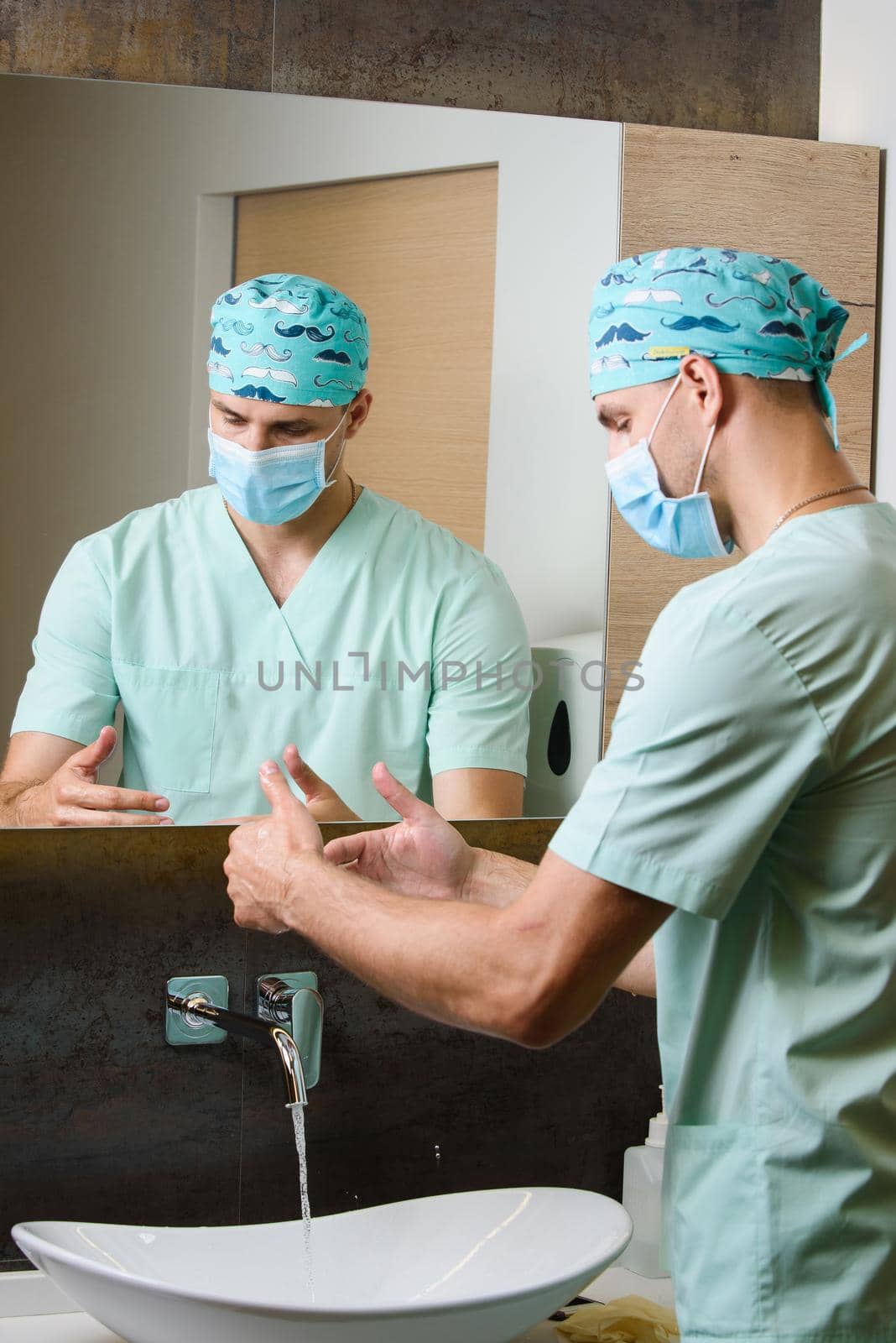 Surgeon is looking at the cleanliness of his hands after washing under a stream of water. Hygiene before working with patients.