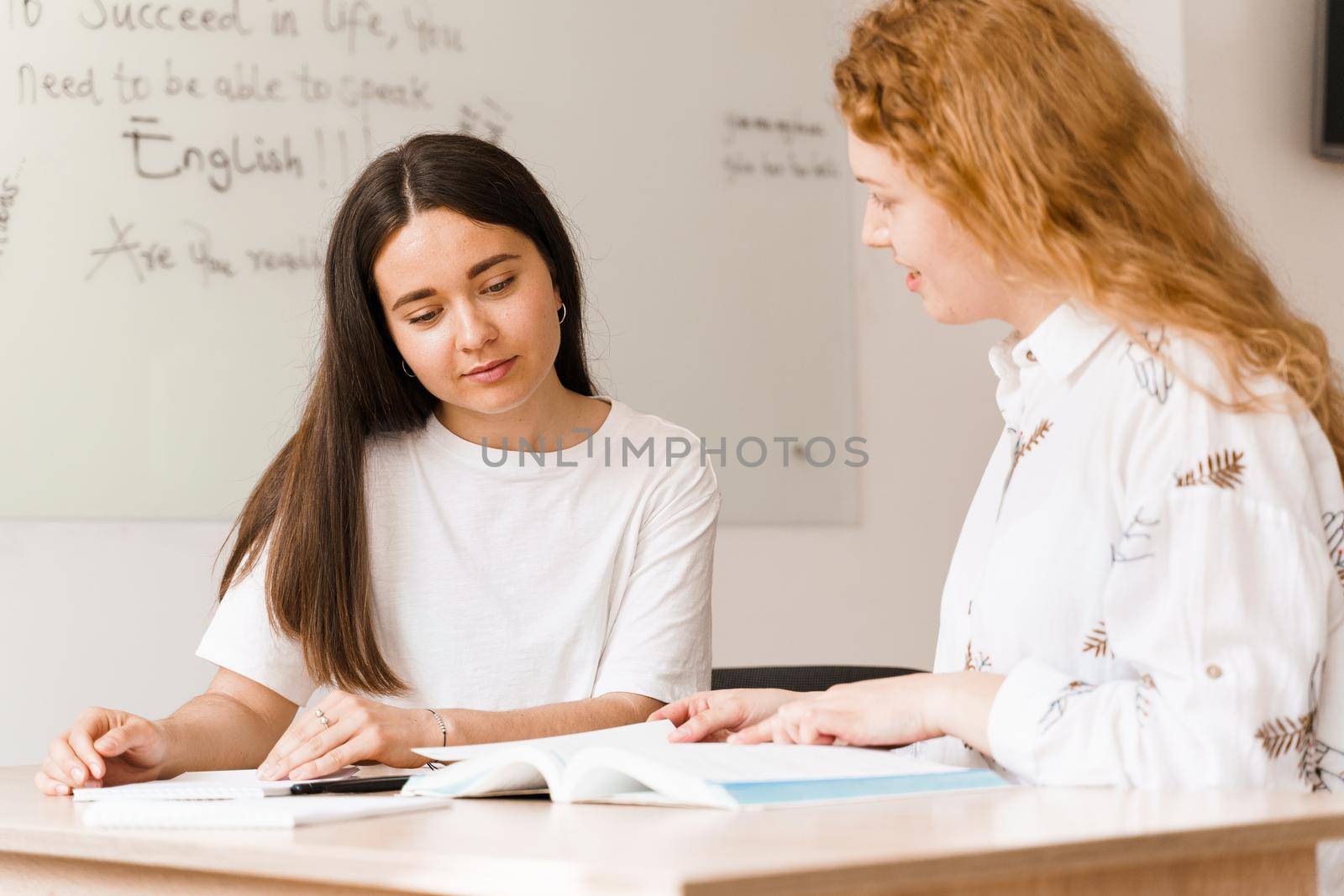 Teacher of english asks student in white class. 2 girls student answers to teacher. Working in group. Study english and british language.