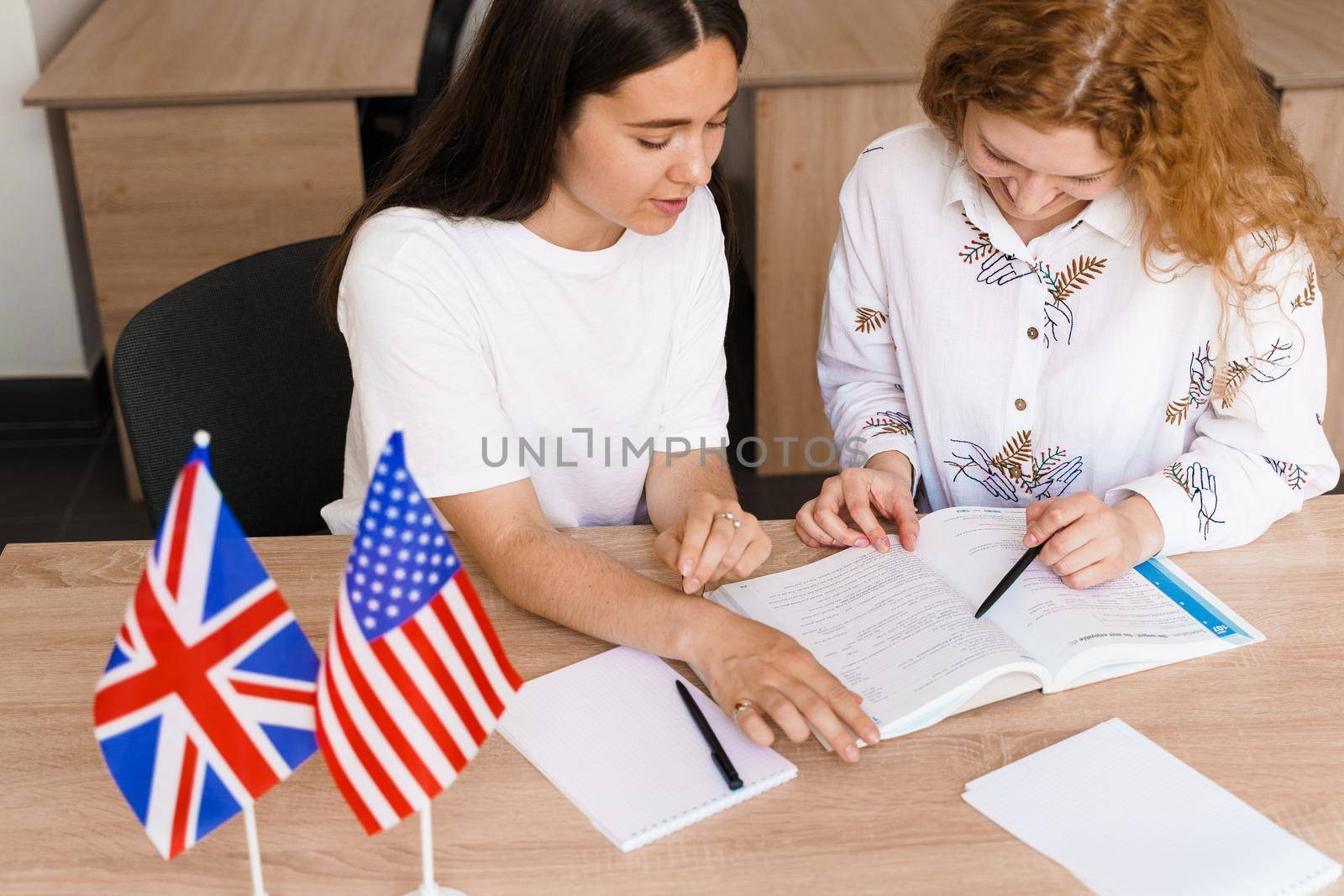 Teacher of english asks student in white class. 2 girls student answers to teacher. Working in group. Study english and british language.