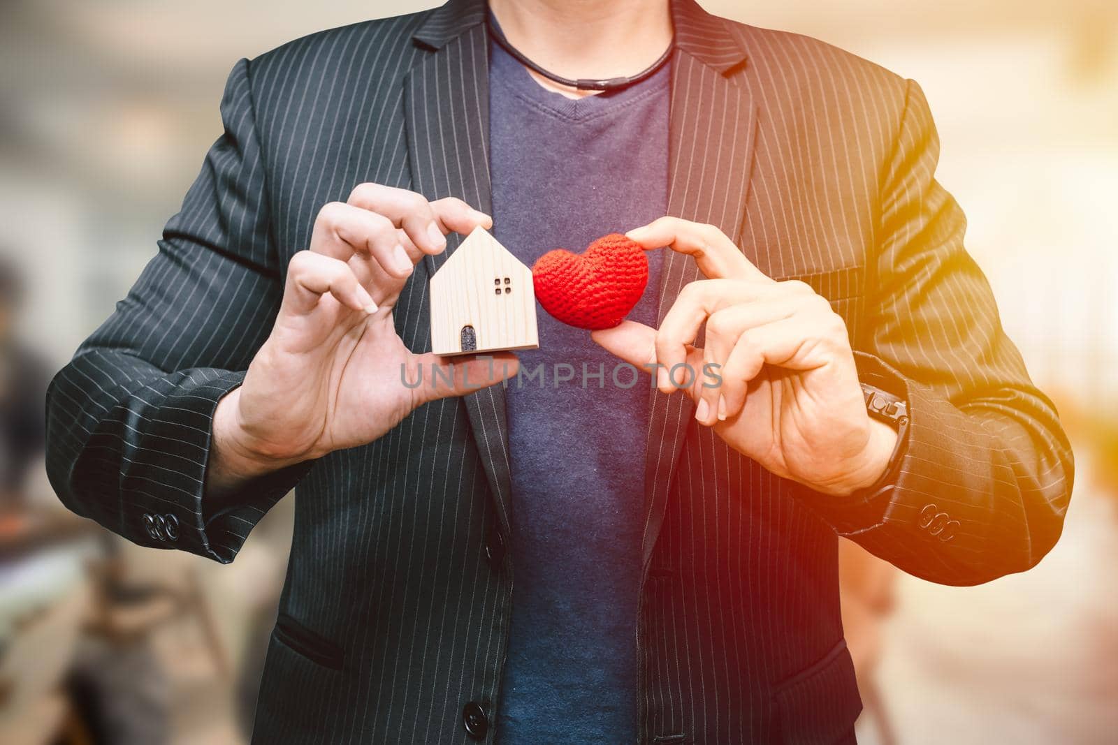 male man hand holding small home and hart sign for love home or business accommodation service concept