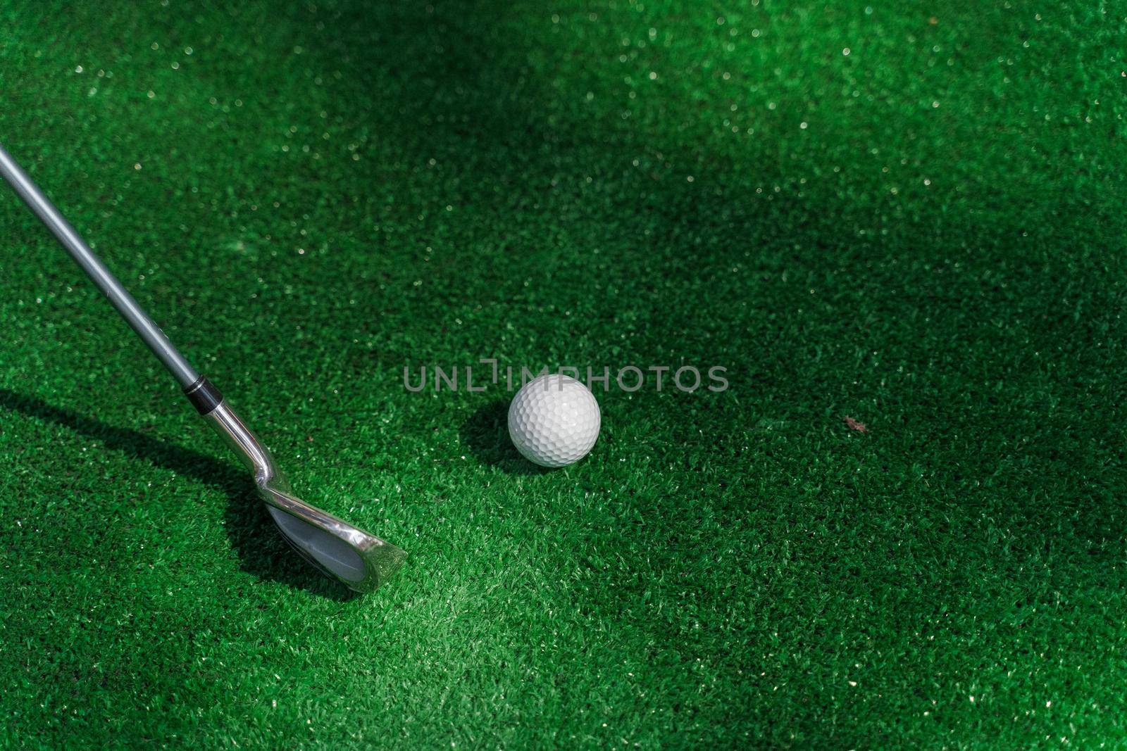 Golf sport game with niblick and white ball on the green grass. Playing in mini golf. Empty place for advert right side.