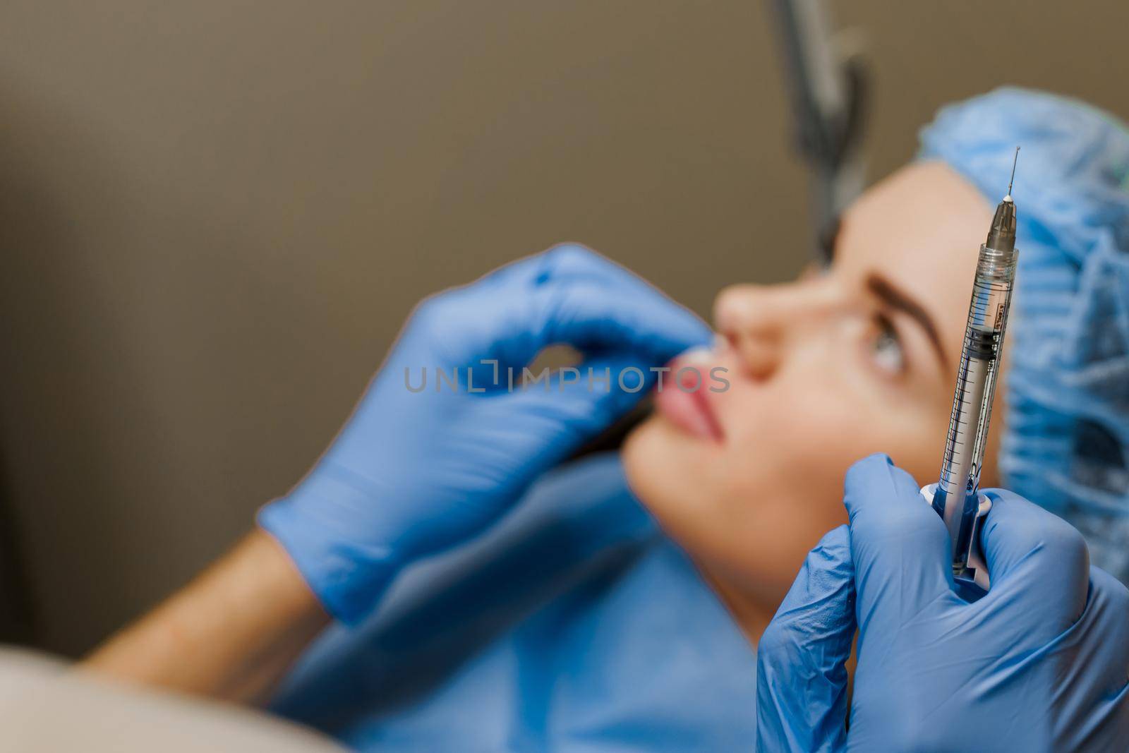 Lips augmentation injections for attractive girl. Plastic surgeon does injection in lip in medical clinic. Cosmetic rejuvenating facial treatment