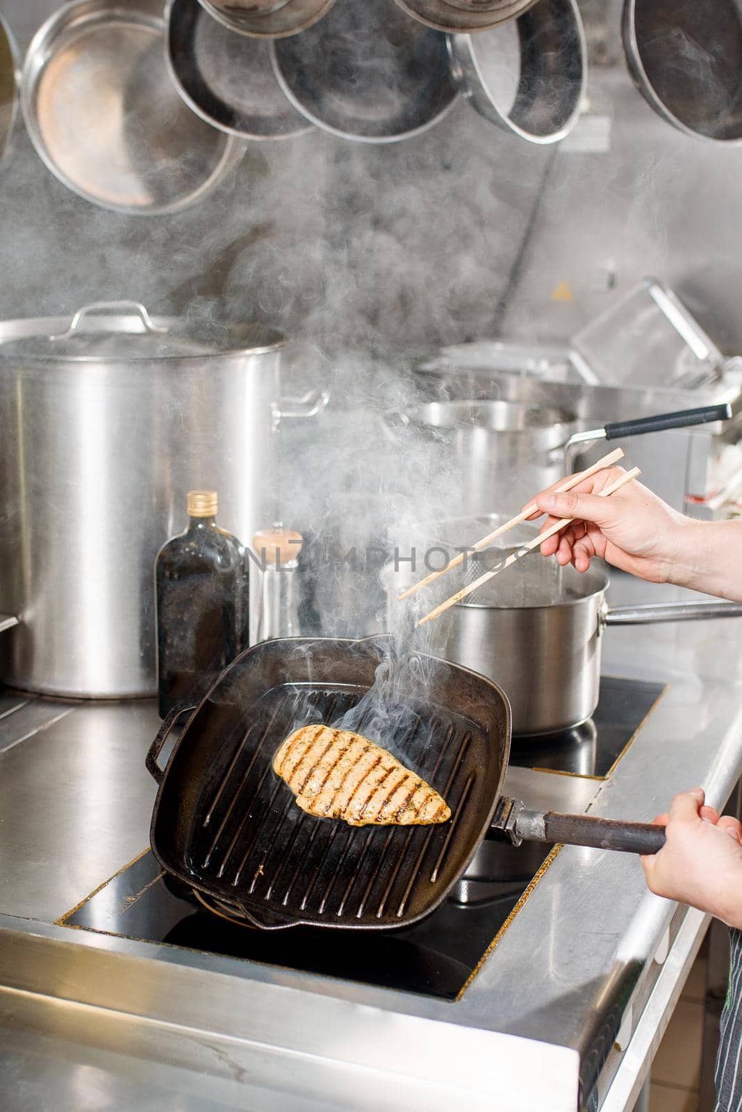 Fried chicken fillet in a pan. Cooking ramen soup. Chef touches chicken with a japanese sticks for food.