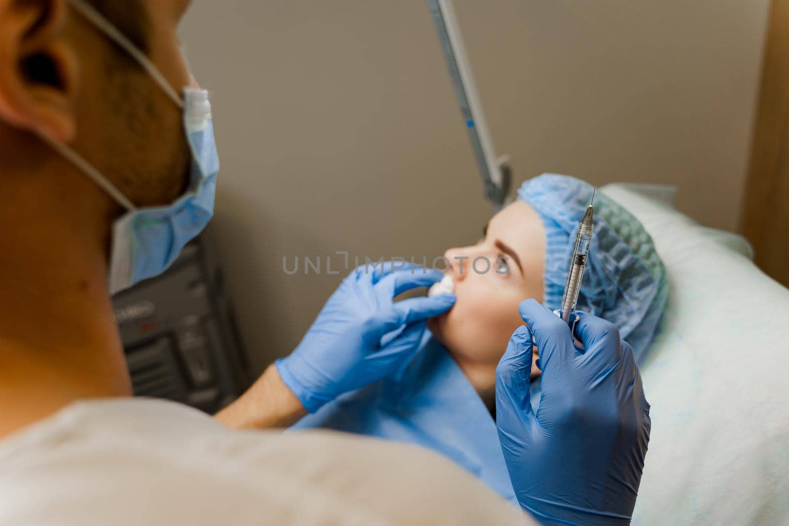 Doctor holds a syringe on the blurred background with patient. Preparation before plastic surgery. Lips Augmentation. by Rabizo