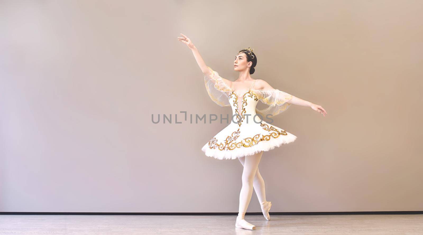 young beautiful woman ballet dancer in a white tutu practicing classical dance steps in studio before performance