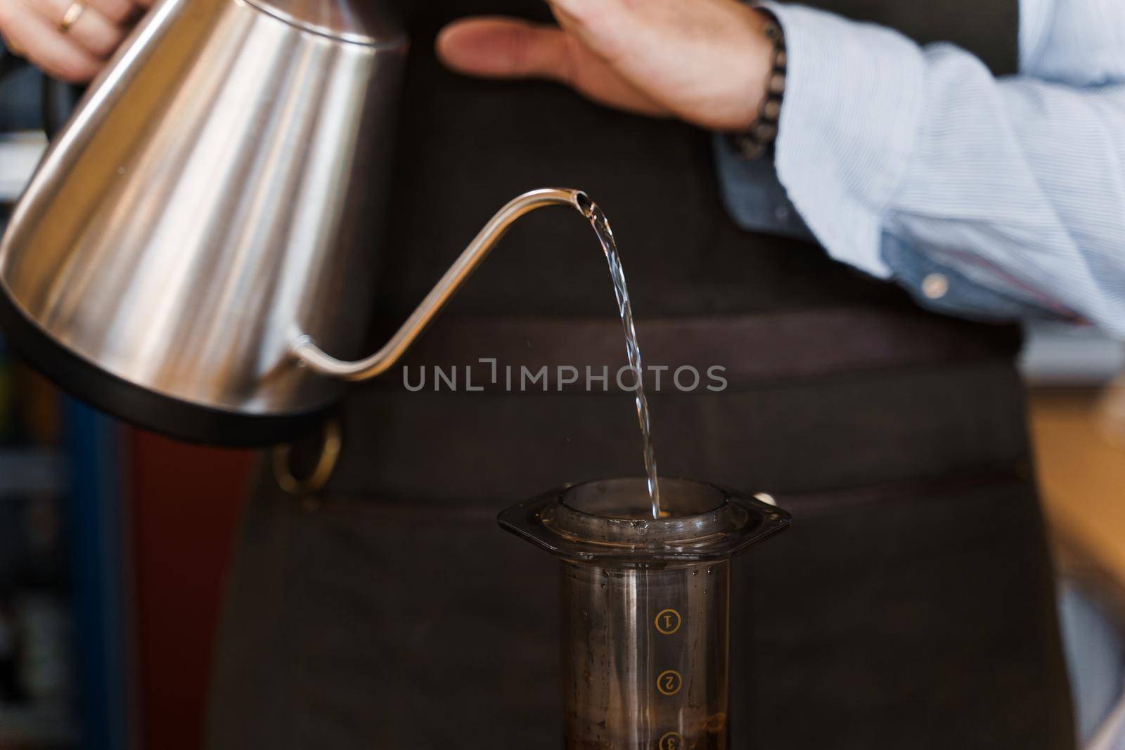 Aeropress coffee alternative making by barista in the cafe. Scandinavian coffee brewing method. Barista pours water to aeropress with coffee