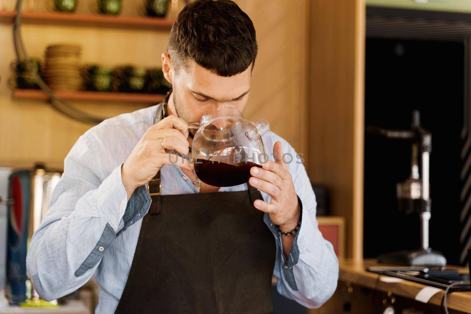 Barista sniffs flavored coffee in glass pot in cafe. Coffee brewing syphon and aeropress alternative methods