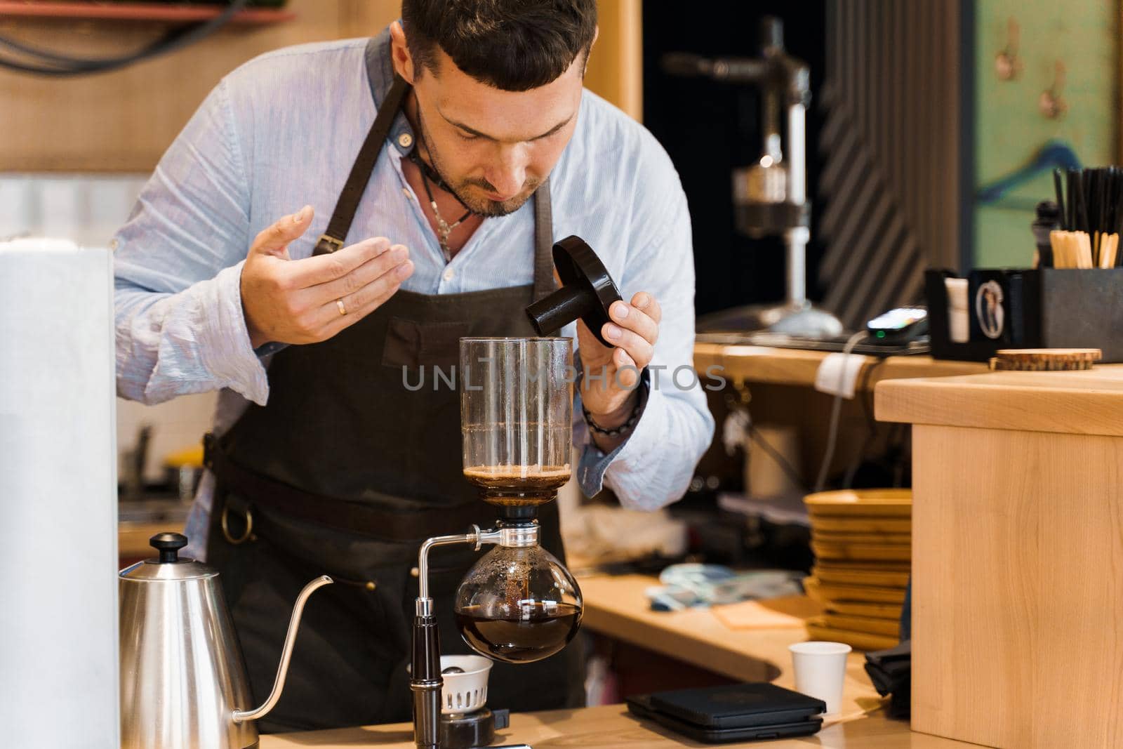 Barista sniffs flavored coffee in syphon device. Barista checks coffee in syphon. Coffee brewing syphon alternative method