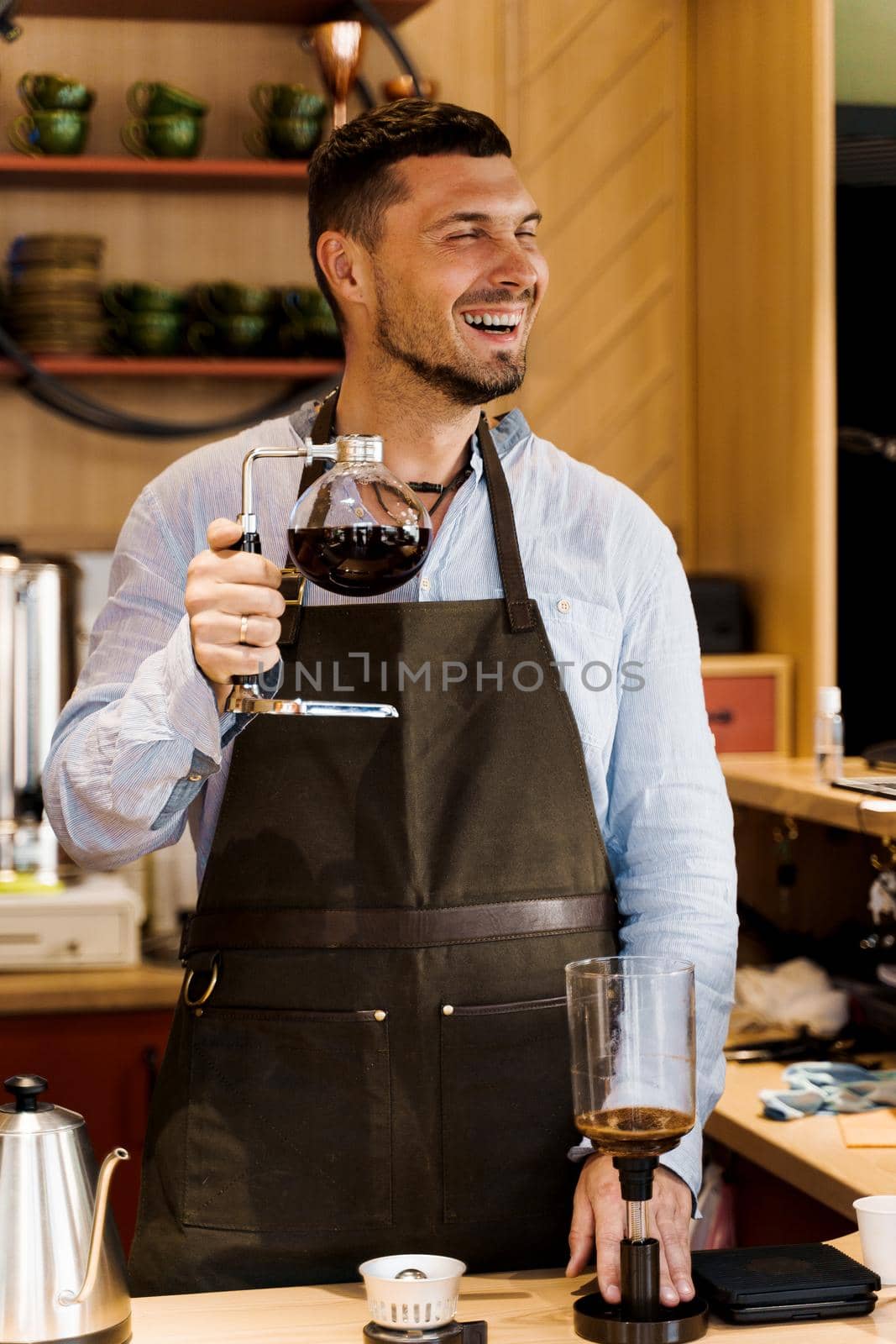 Barista jokes and smiles with syphon coffee making in cafe. Altertanive coffee brewing process