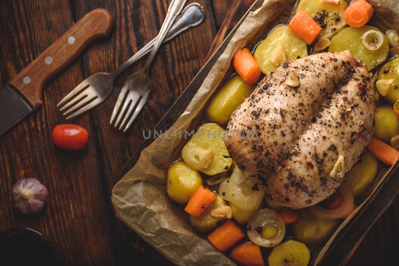 Seasoned chicken breast baked in oven with vegetables on baking sheet