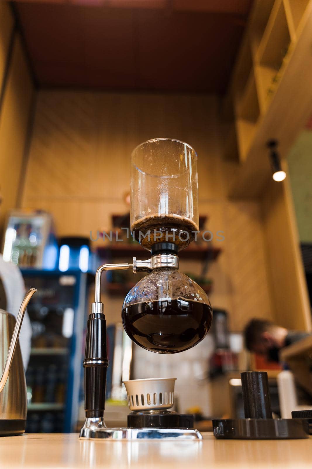 Syphon coffee brewing process. Close-up syphon is heating by fire. Barista looking at alternative coffee brewing process on the fire