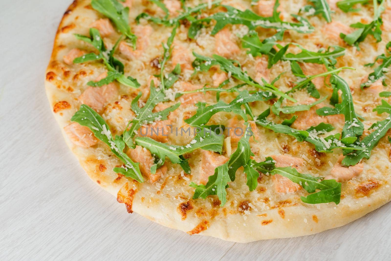 Pizza with salmon, parmesan and arugula isolated on white wooden background. Advert for social network of restaurants, caffee. Promotion for pizzeria.