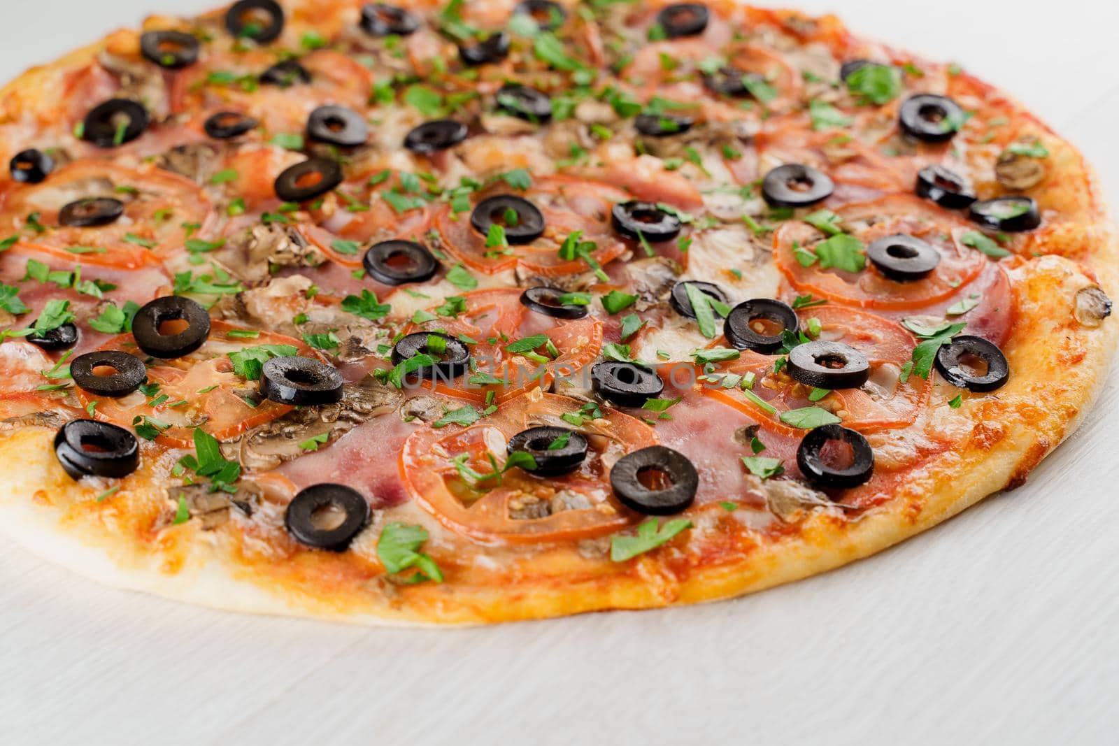 Pizza with meat, olives, tomatoes, mushrooms, herbs isolated on white wooden background. Advert for social network of restaurants, caffee. Promotion for pizzeria