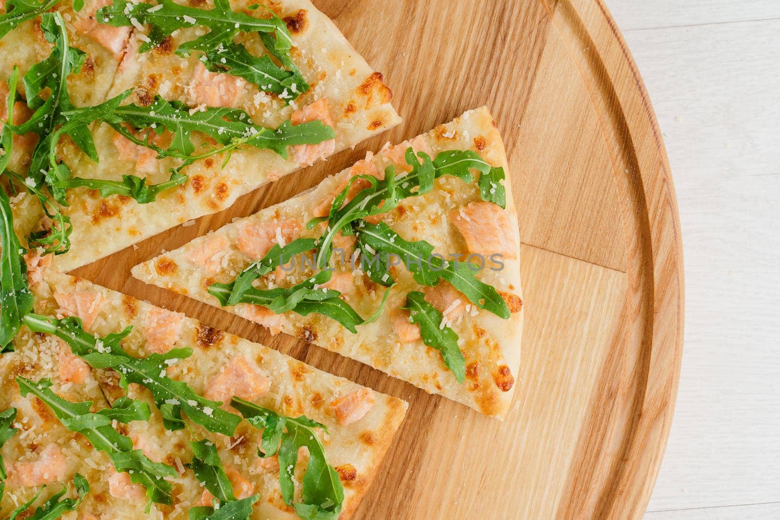 Pizza with salmon, parmesan and arugula isolated on white wooden background. Advert for social network of restaurants, caffee. Promotion for pizzeria.