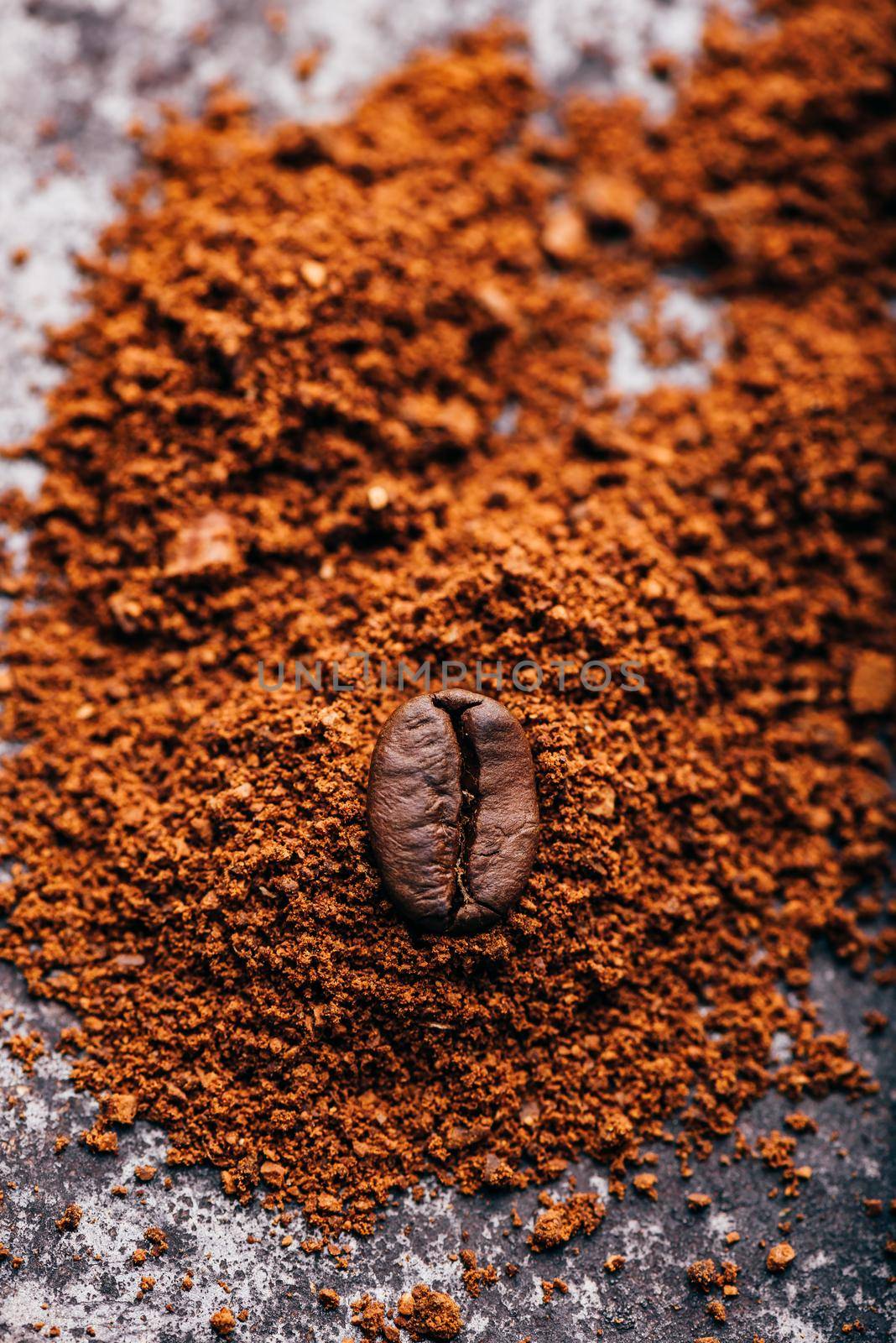 Fresh roasted coffee bean lays on heap of grinded coffee