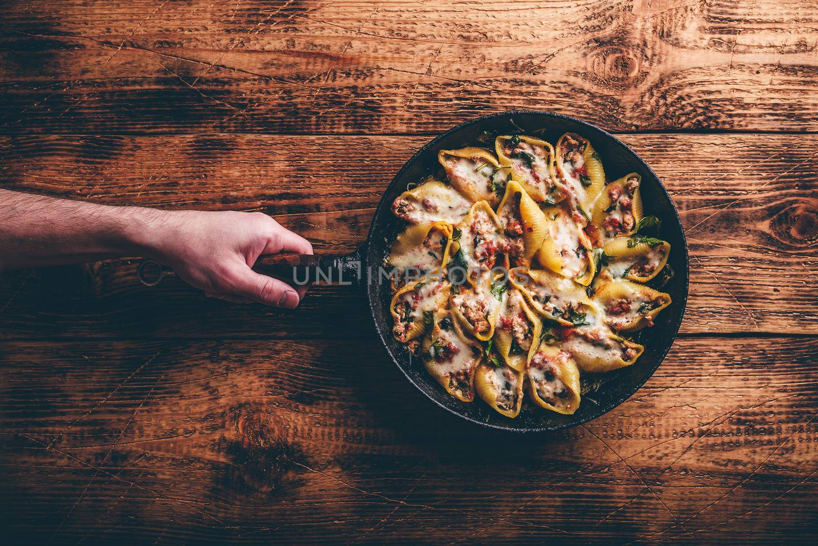 Skillet of baked jumbo shells pasta stuffed with ground beef, spinach and cheese