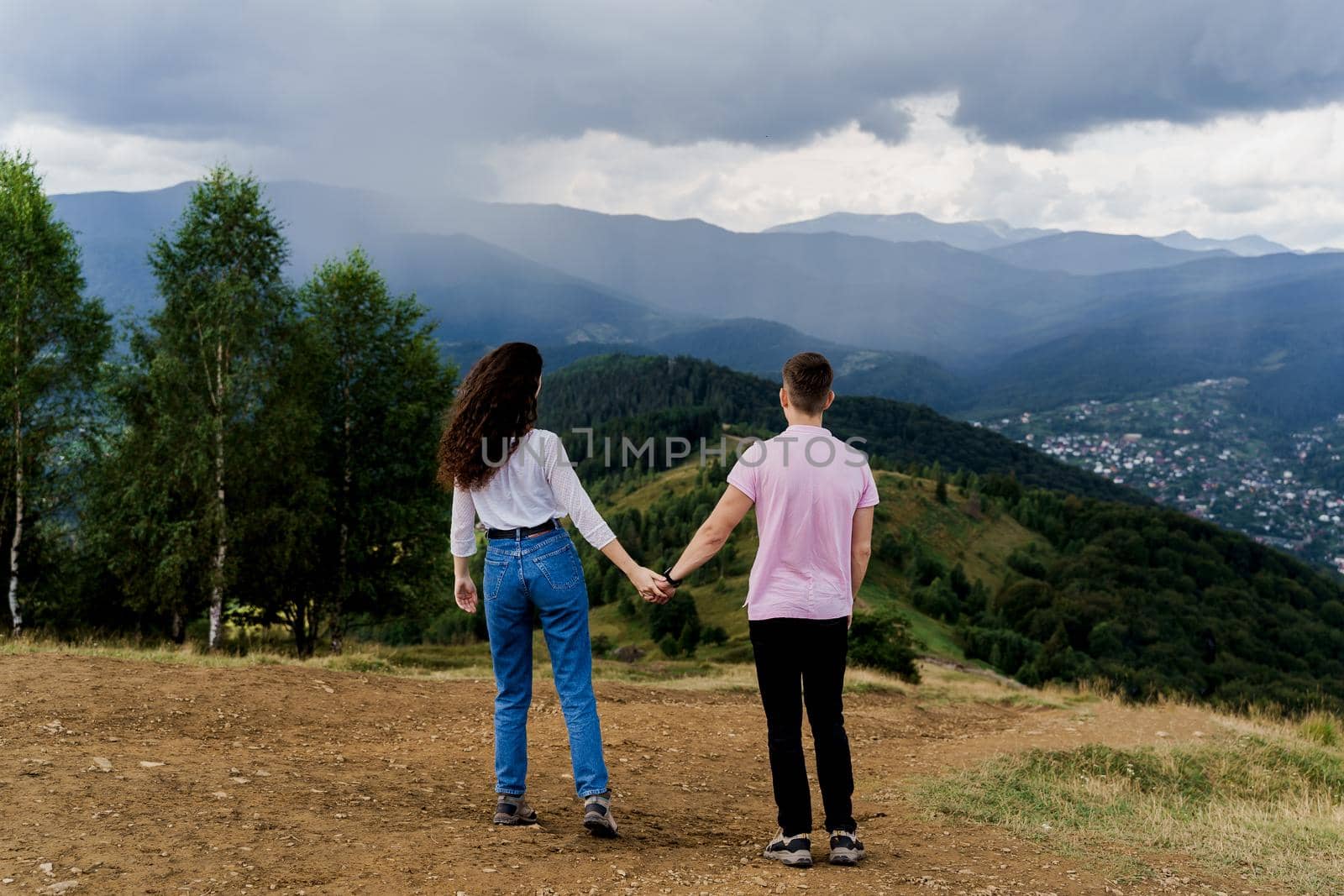Couple looking at the mountain hills before raining. Feeling freedom together in Karpathian mountains. Tourism travelling in Ukraine by Rabizo