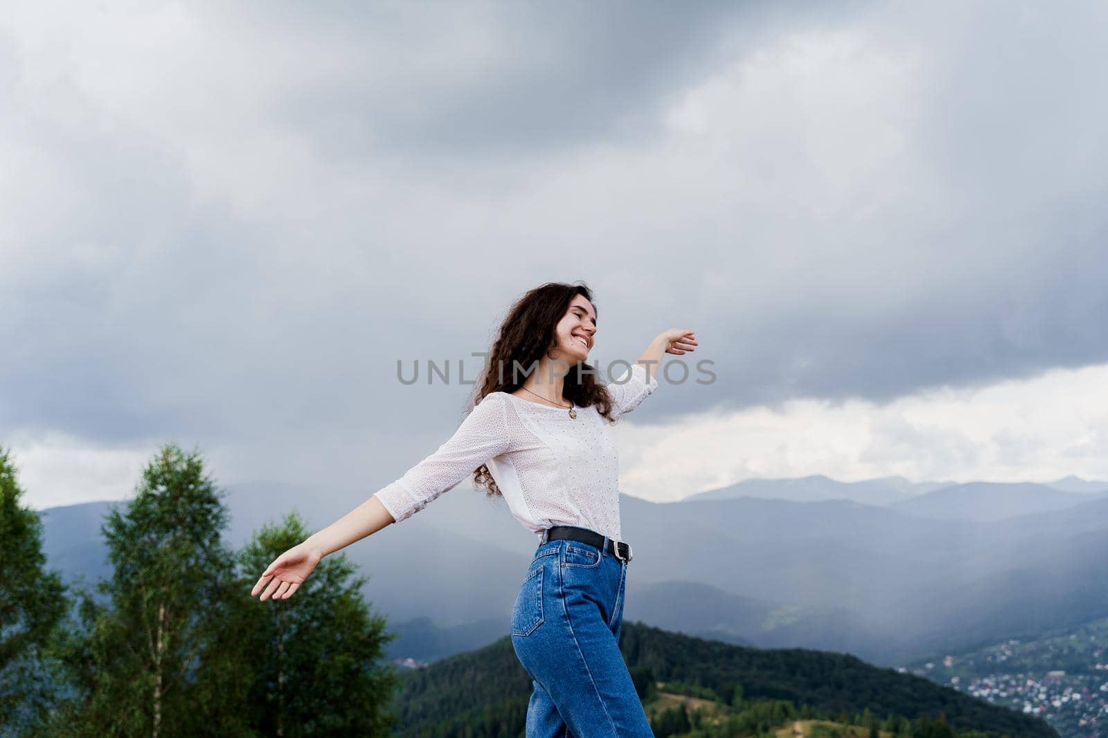 Feeling freedom in Karpathian mountains. Tourism travelling in Ukraine. Girl girl raised her hands up and enjoys the mountain hills view.