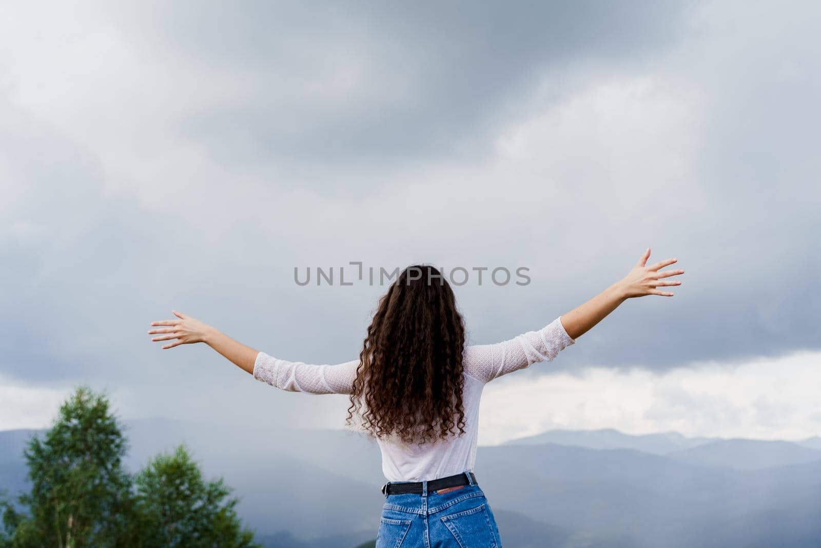 Feeling freedom in Karpathian mountains. Tourism travelling in Ukraine. Girl girl raised her hands up and enjoys the mountain hills view.
