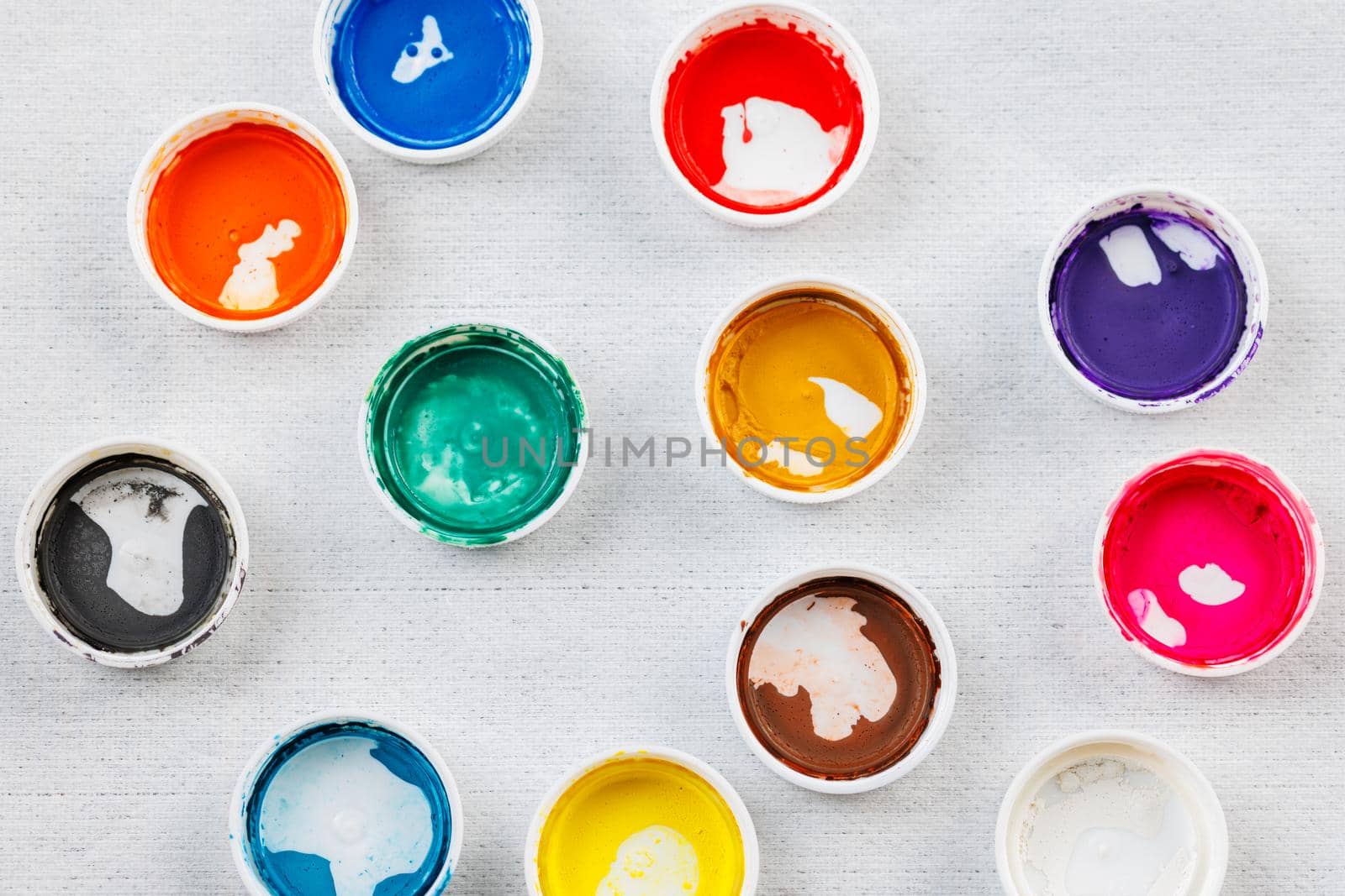 full-frame close-up background of gouache paint jar caps on white cloth background