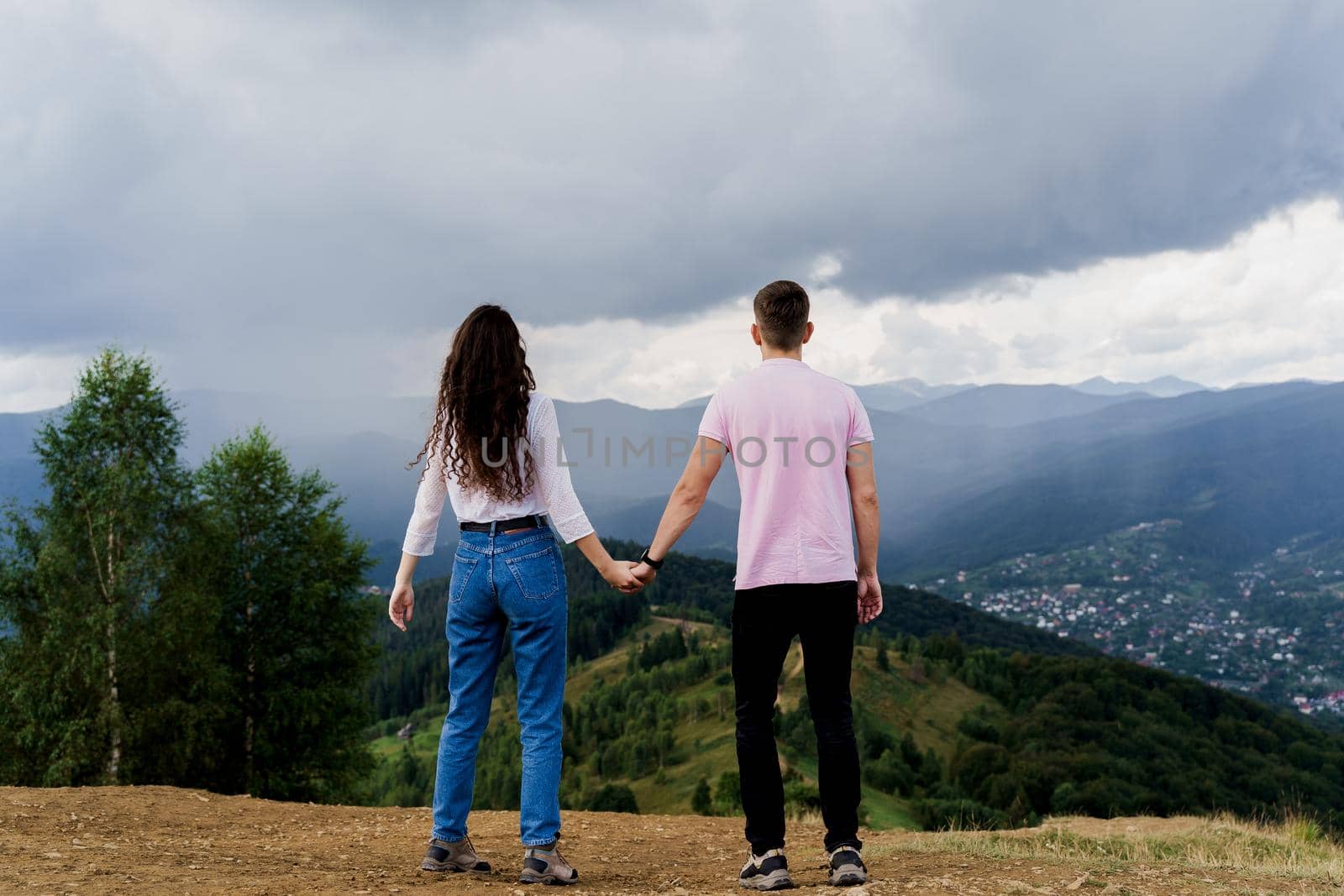 Couple looking at the mountain hills before raining. Feeling freedom together in Karpathian mountains. Tourism travelling in Ukraine by Rabizo