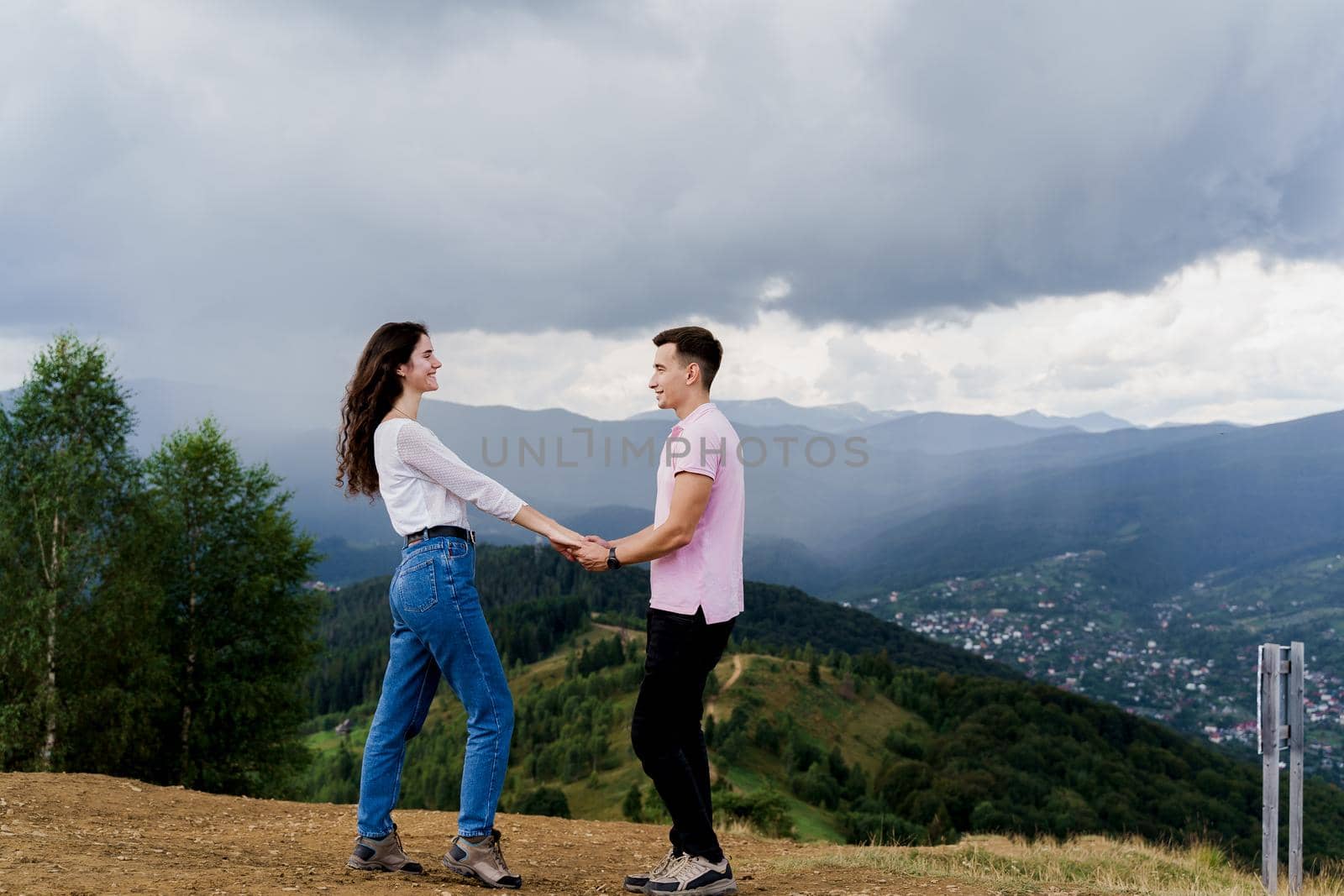 Couple looking to each other at the mountain hills before raining. Feeling freedom together in Karpathian mountains. Tourism travelling in Ukraine.
