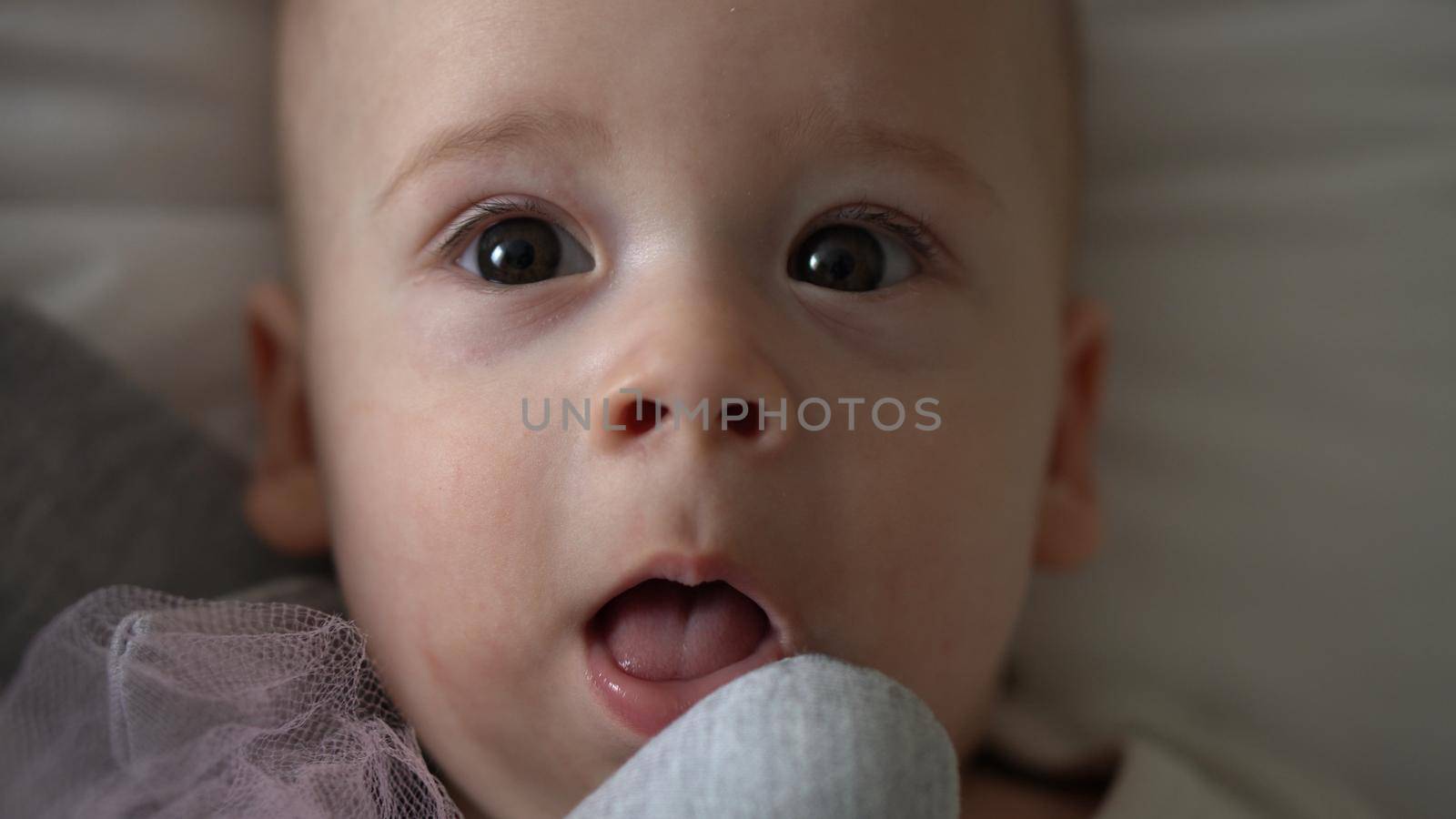 Close-up Happy playful kid 6 month old. Newborn boy looking at camera after bath shower on white soft bed. baby child waking time before bedtime with Toy. Childhood, motherhood, family, infant concept.