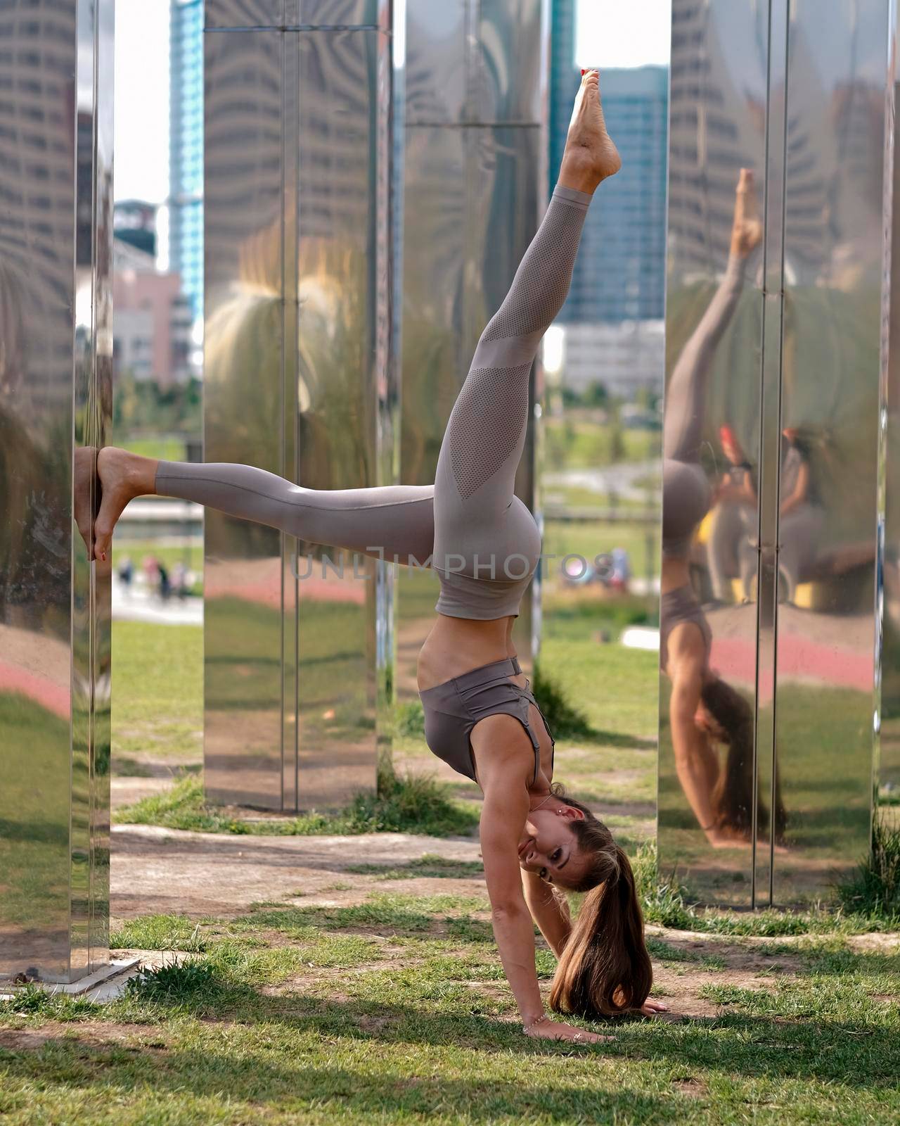Young woman doing yoga exercises with city on background. Beautiful asana on hands, balance