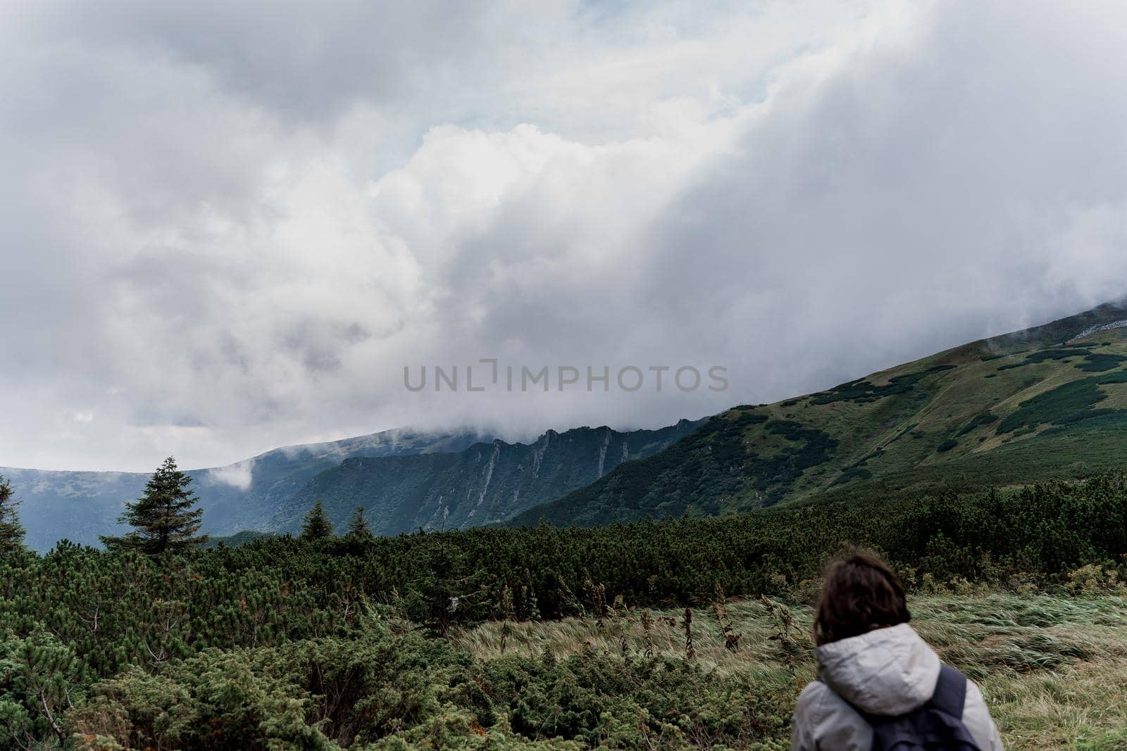 Girl is travelling in the mountains. Foggy day. Hiking and climbing up to the peak of the mountain. Beautiful nature of Ukraine.