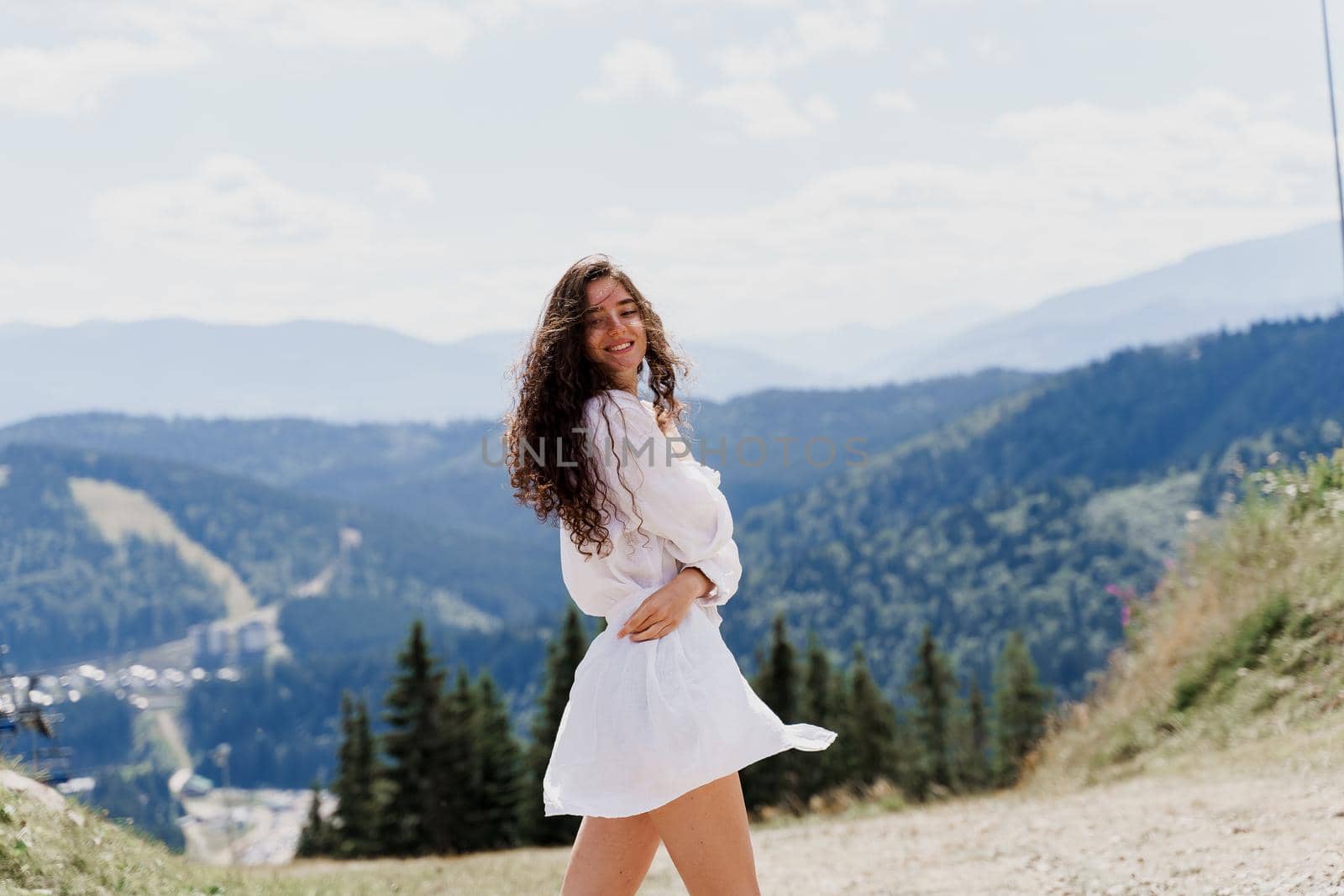 Girl traveler is smiling in the mountains. Attractive woman posing on the green hills background. Advert for travel agency. Tourism