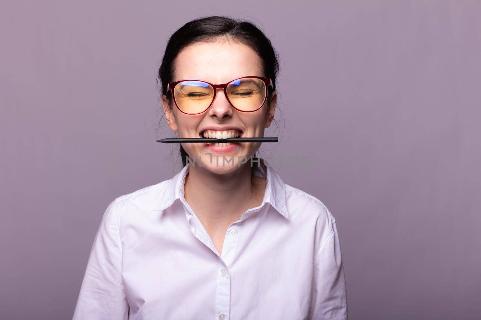 woman in a white shirt and glasses holds a pen with her mouth. High quality photo