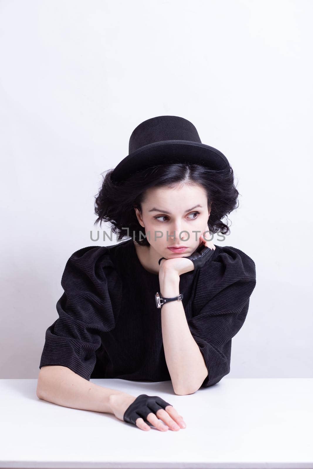 A woman in a hat and fingerless gloves sits at a table. High quality photo