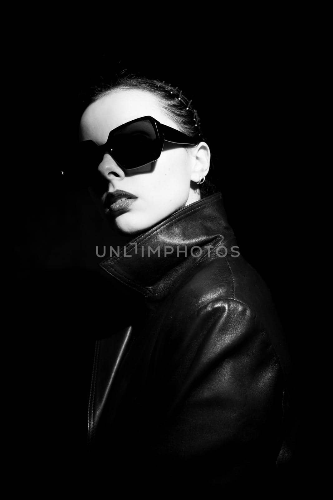 woman in leather coat and sunglasses, black background. High quality photo