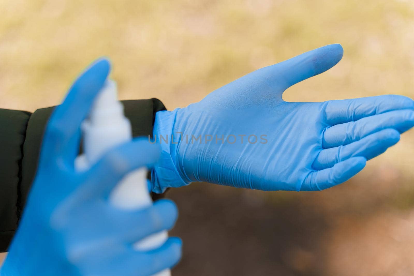 Spraying antiseptic to hand in blue medical gloves. Pandemic of sars cov 2. Cleaning hands. Desinfection