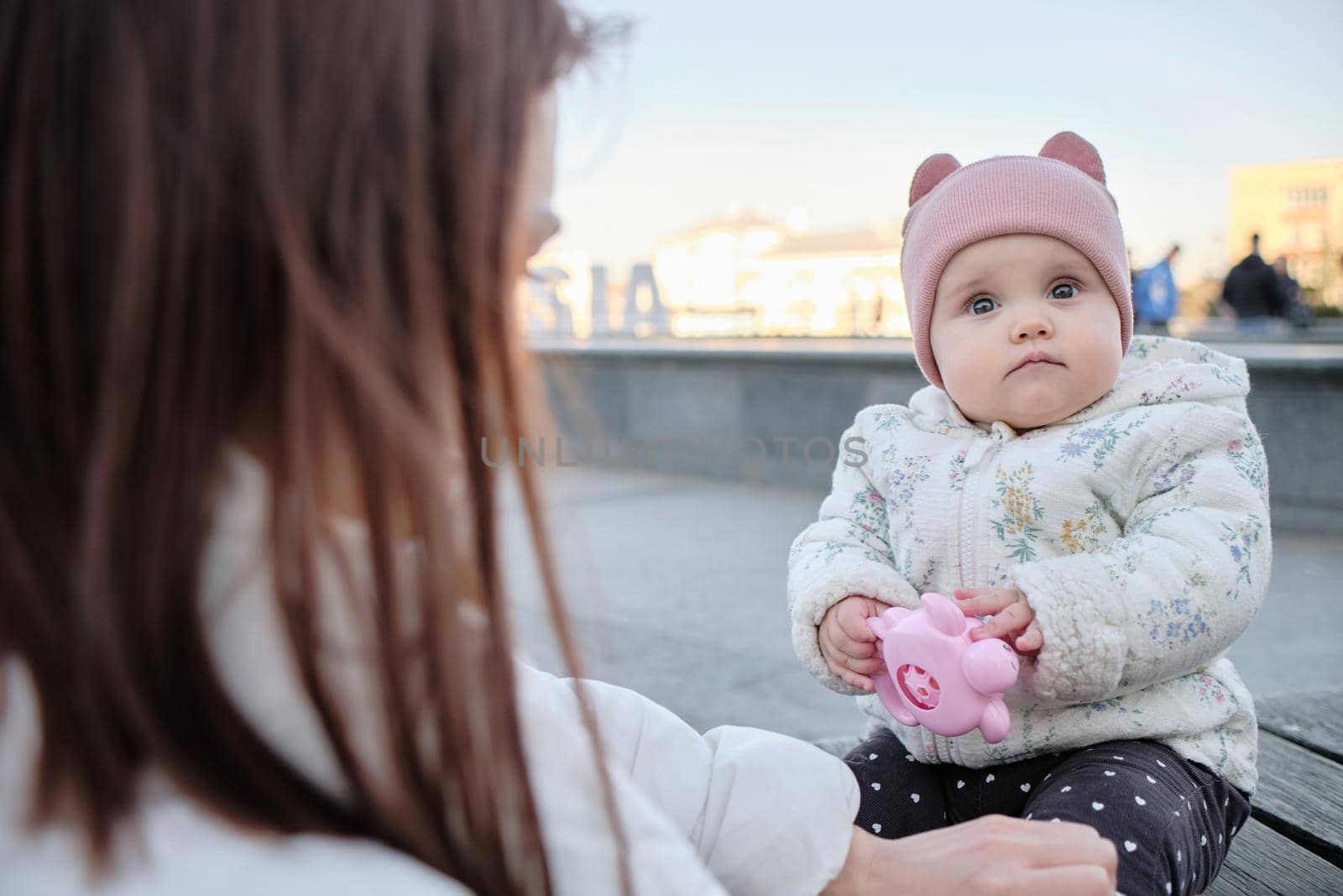 Young mother with her cute baby on bench in park