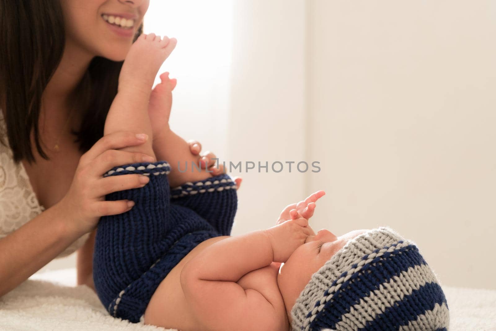 Latin young mother kisses baby feet and sniff them on the bed at home by FranciscoStockLife
