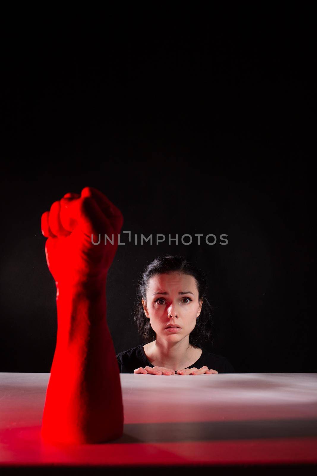woman afraid of red hand, symbol of dictatorship, black background. High quality photo