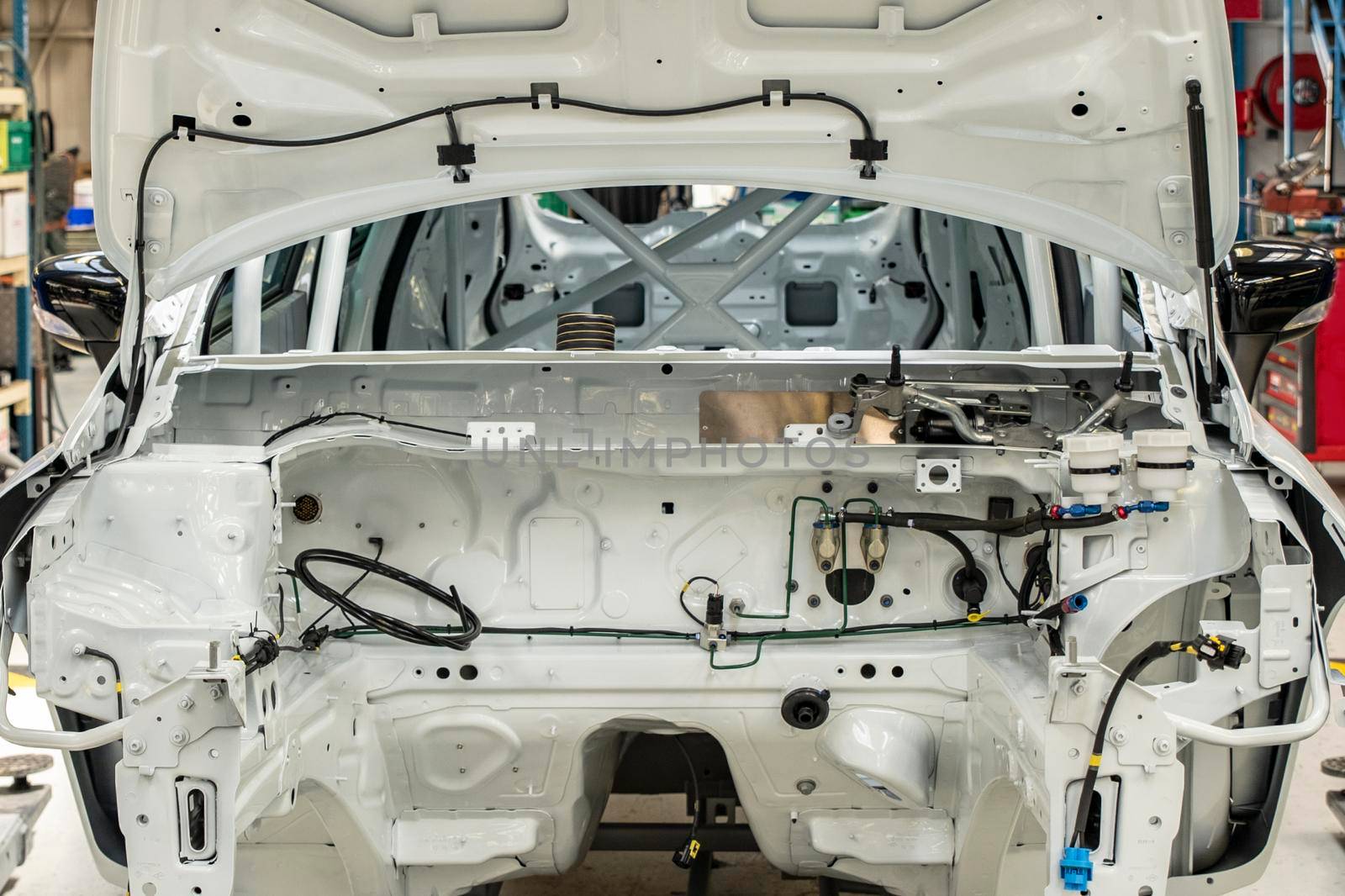 New white car with open hood at a factory
