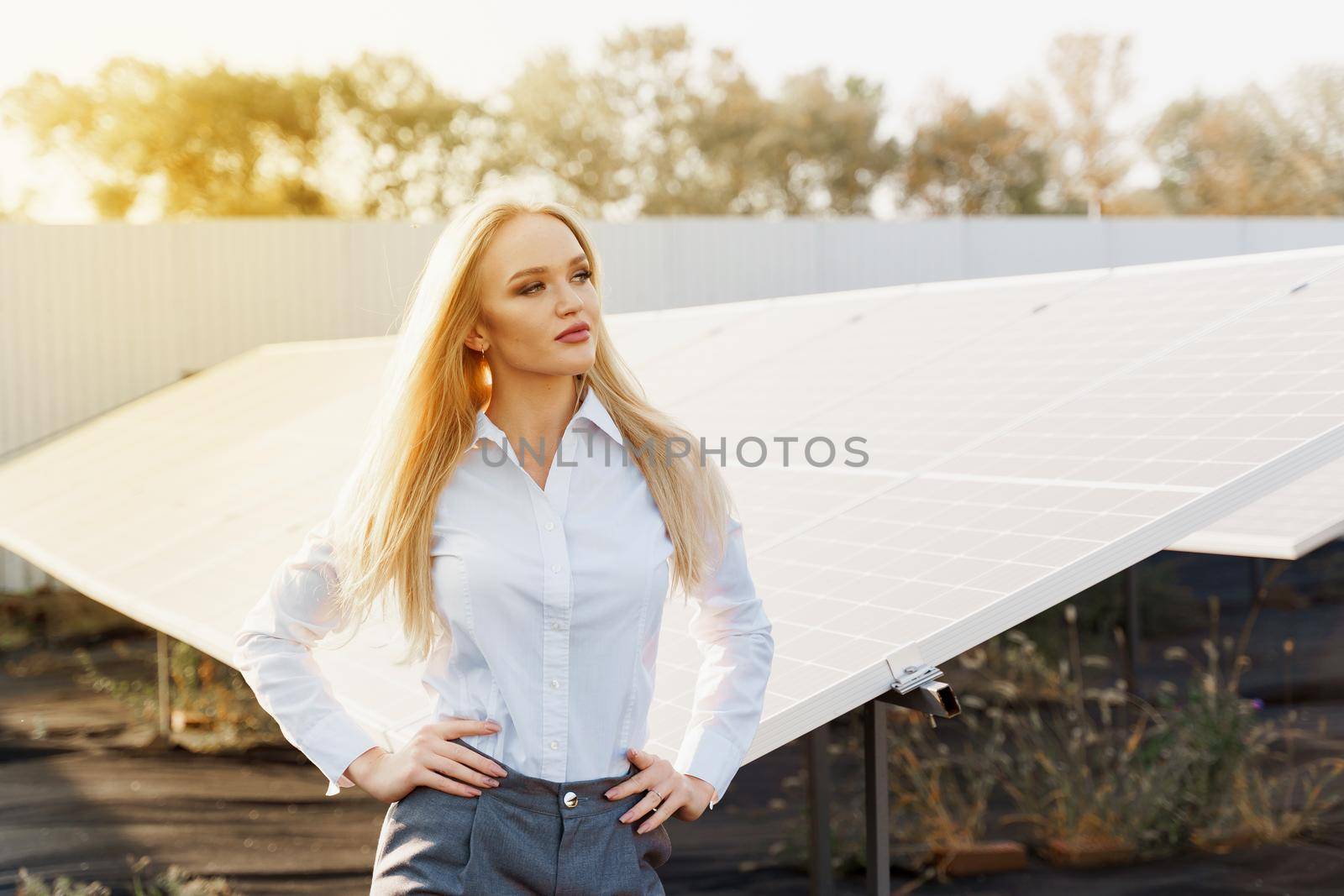 Girl stand and look right side near solar panels row on the ground with sun light. Free electricity for home. Sustainability of planet. Green energy