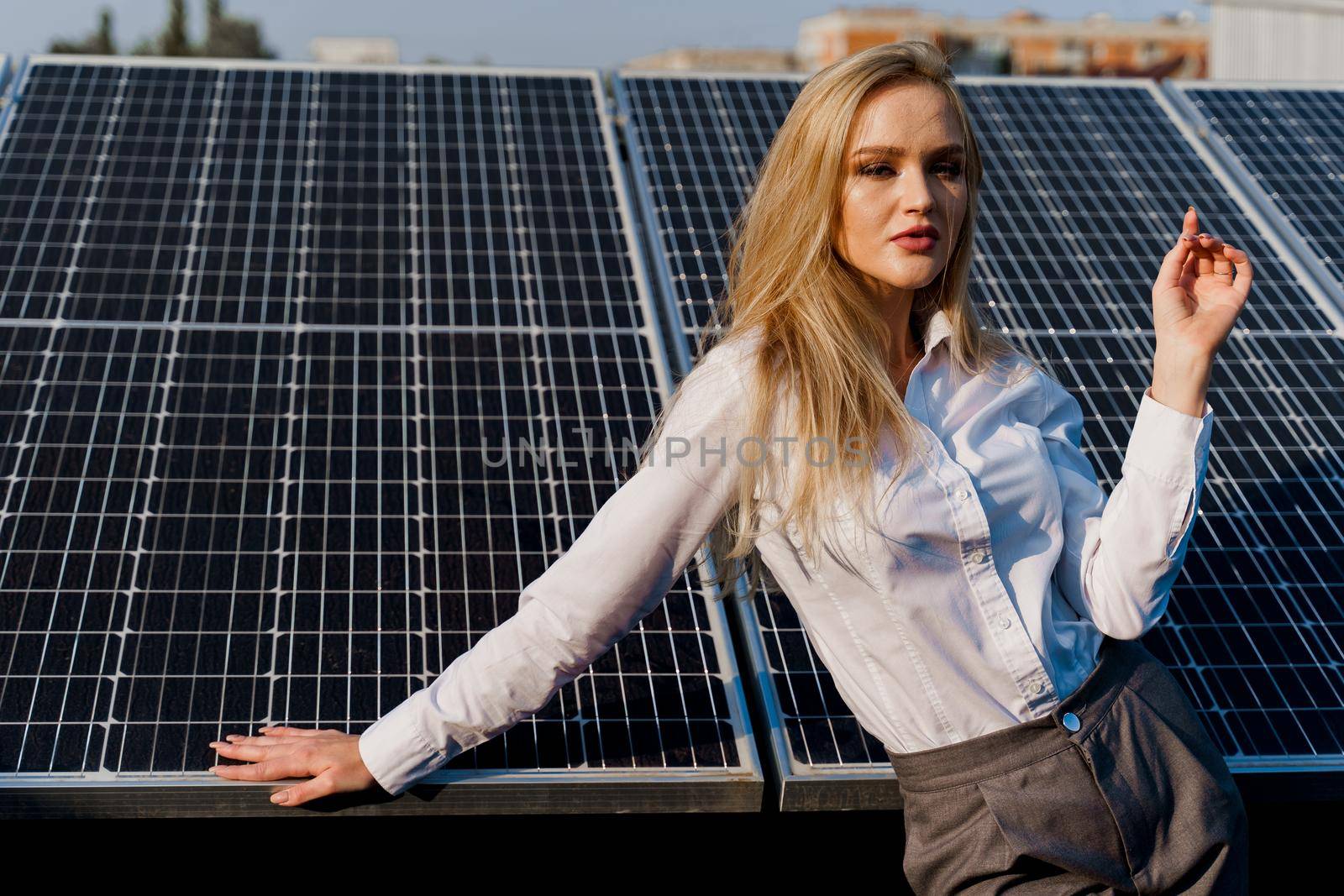 Girl and solar panels stands in row on the ground at sunset. Free electricity for home. Green energy. Solar cells power plant for business