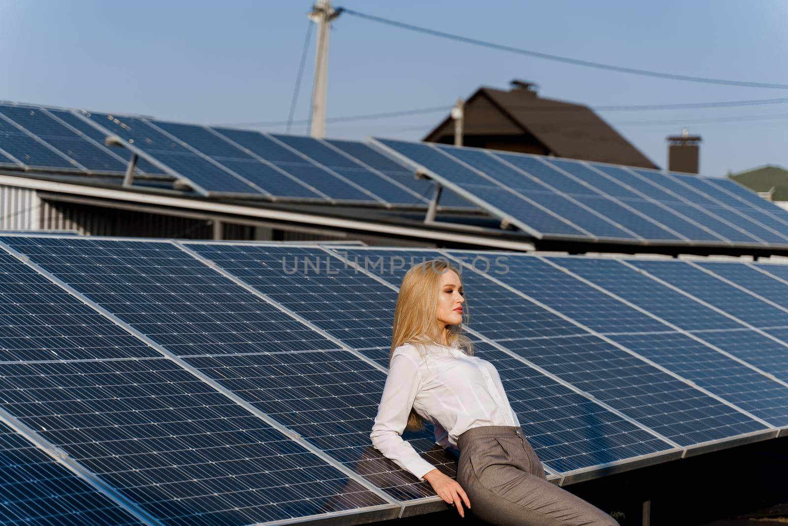 Girl and solar panels stands in row on the ground at sunset. Free electricity for home. Green energy. Solar cells power plant for business