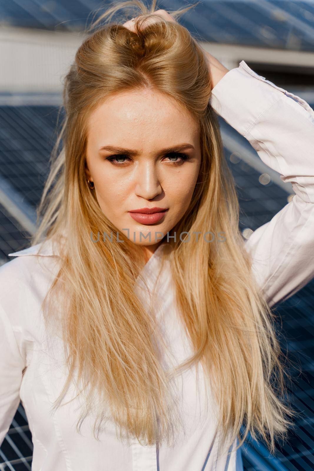 Close-up portrait of blonde model near solar panels. Free electricity for home. Green energy. Solar cells power plant business