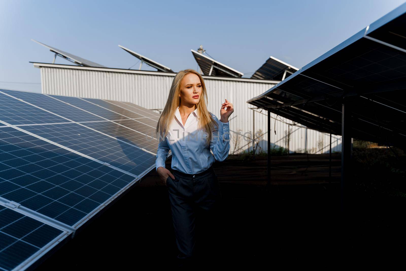 Girl walks between 2 Solar panels row on the ground at sunset. Free electricity for home. Sustainability of planet. Green energy.
